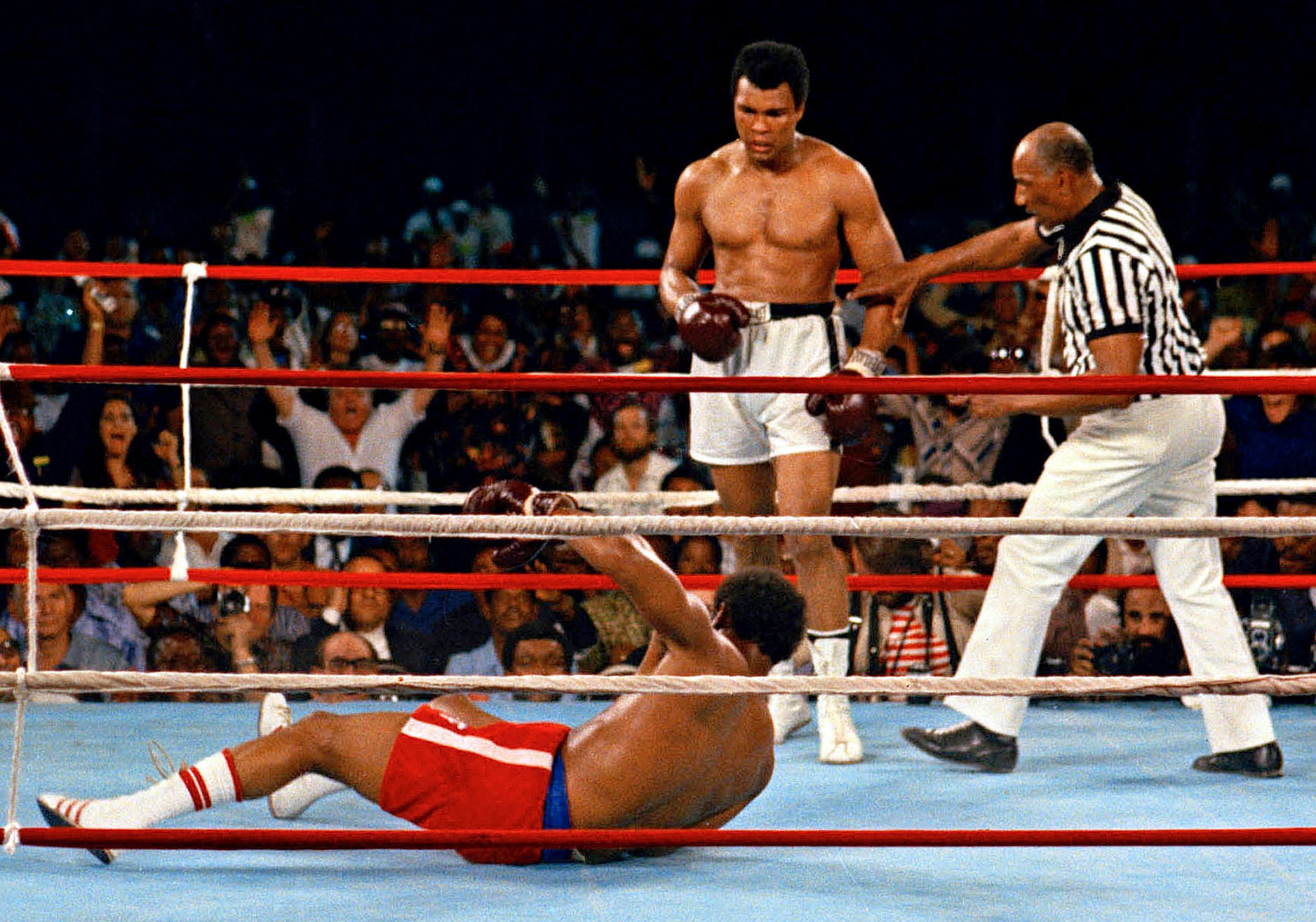 Muhammad Ali (center) watches after knocking down defending heavyweight champion George Foreman. (AP)