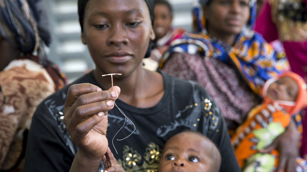 A woman in a rural area of Kenya examines an intrauterine device during a visit from a outreach team sent by a family planning organization.