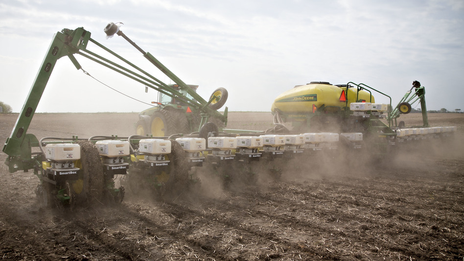 A tractor pulls a planter while distributing corn seed on a field in Malden, Ill. Two scientists agree that pesticide-laden dust from planting equipment kills bees. But they're proposing different solutions, because they disagree about whether the pesticides are useful to farmers.