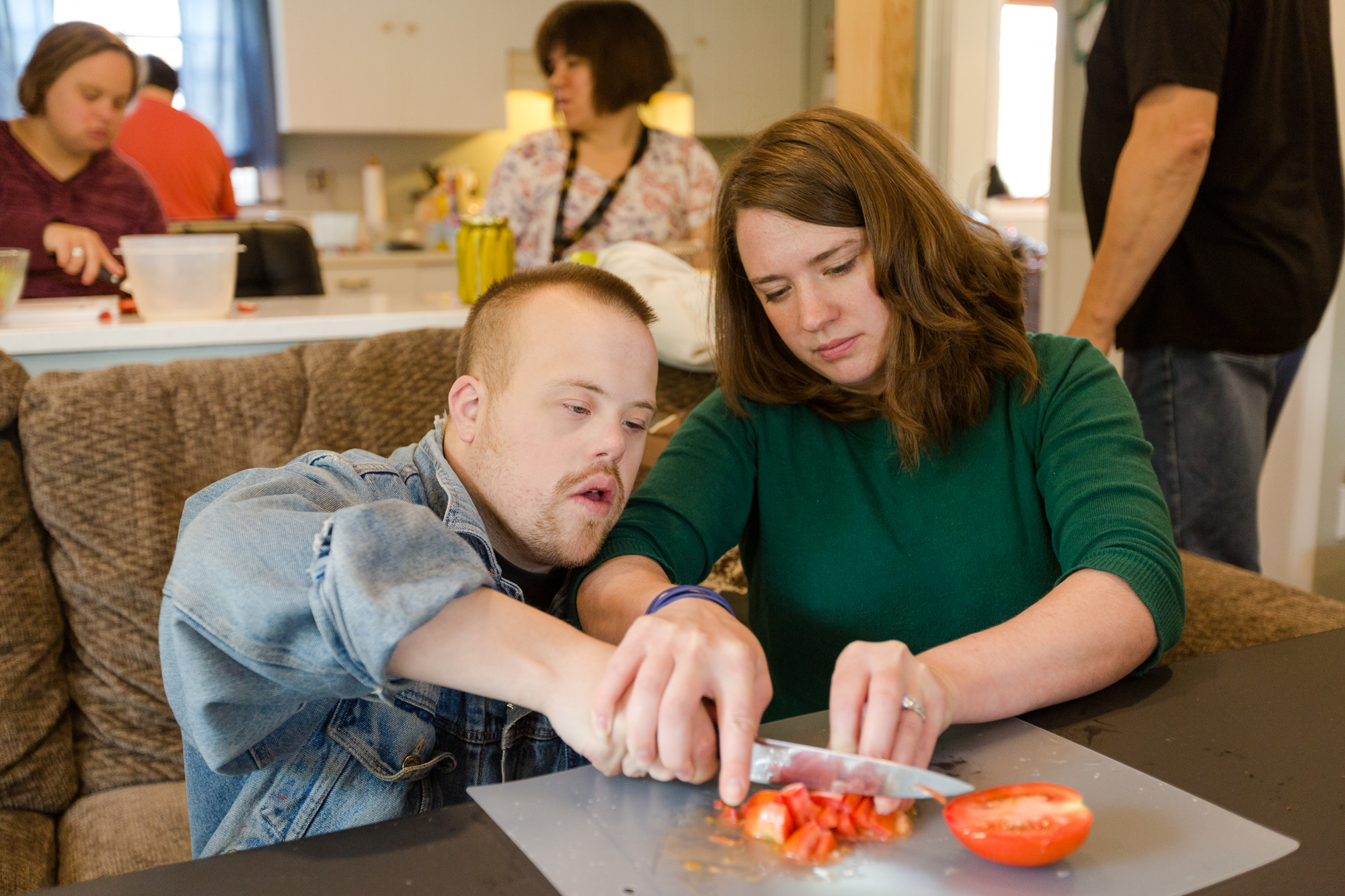 Justine Orr (right), program manager for Our Place Day Services, helps David Breuer chop tomatoes during a cooking class at the center north of Milwaukee. Nearly all the center's clients pay for services with funds from Medicaid. (Sara Stathas for NPR)