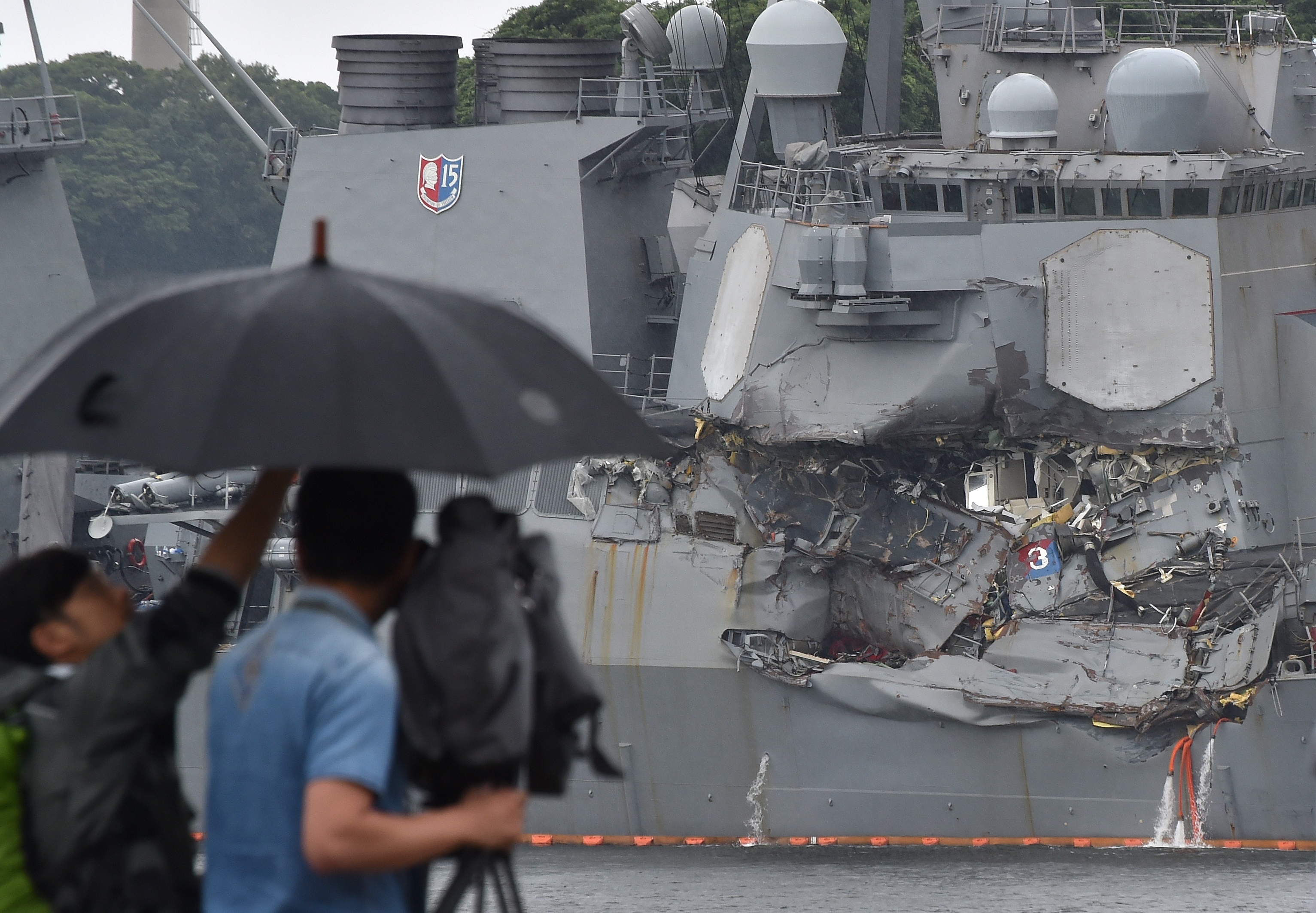 A TV crew films the damage to the USS Fitzgerald at its port in Yokosuka, Japan, on Sunday. &quot;A number&quot; of missing American sailors have been found dead in flooded areas of the destroyer, the U.S. Navy says. (AFP/Getty Images)