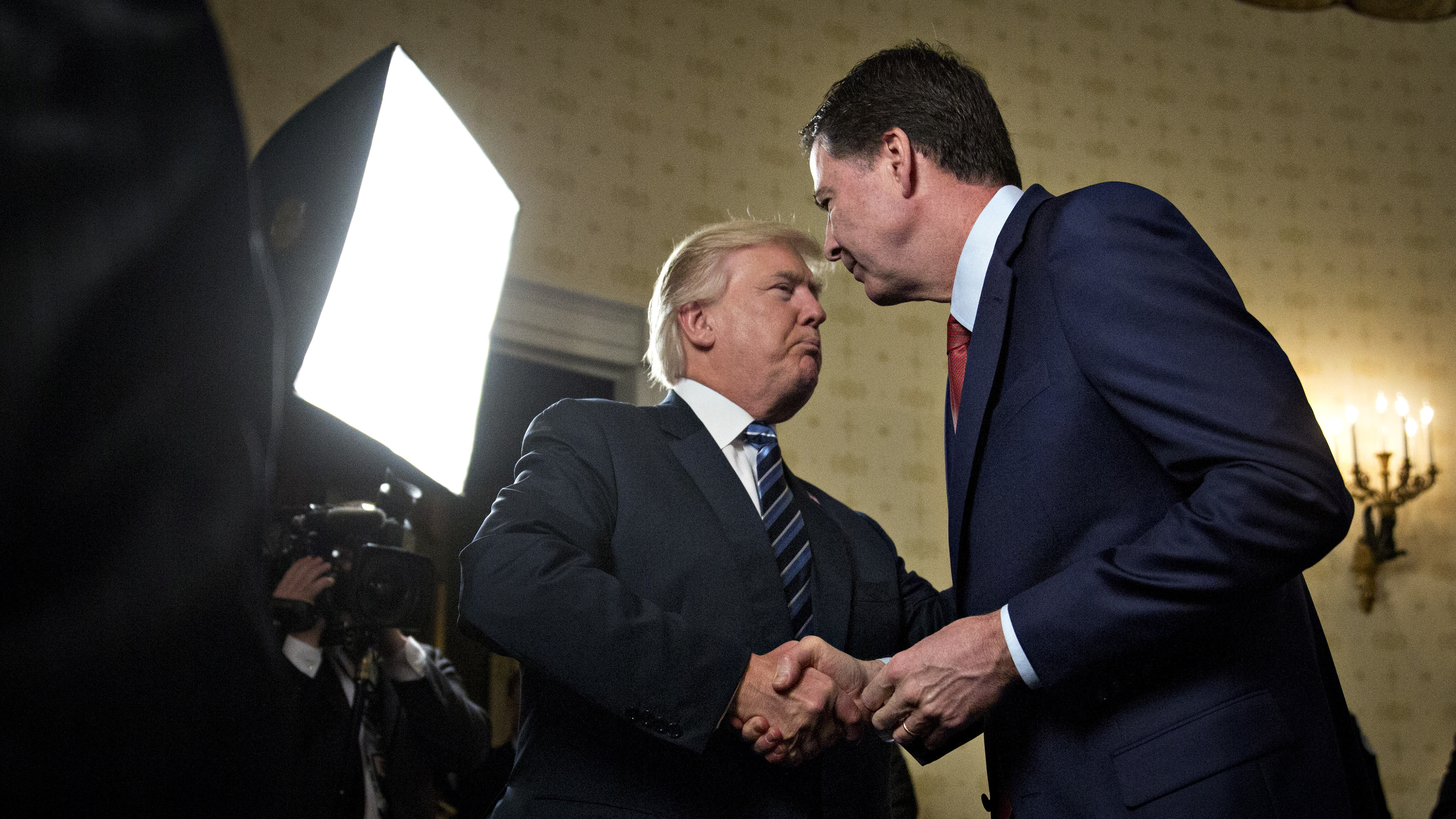 President Trump shakes hands with James Comey, then-director of the FBI, during a reception at the White House on Jan. 22. (Getty Images)