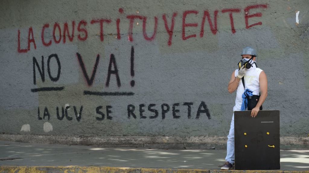 During a protest in Caracas this week, an opposition activist stands near graffiti against a proposal by Venezuelan President Nicolas Maduro to rewrite the constitution. A political and economic crisis has spawned often violent demonstrations by protesters demanding Maduro's resignation. (AFP/Getty Images)
