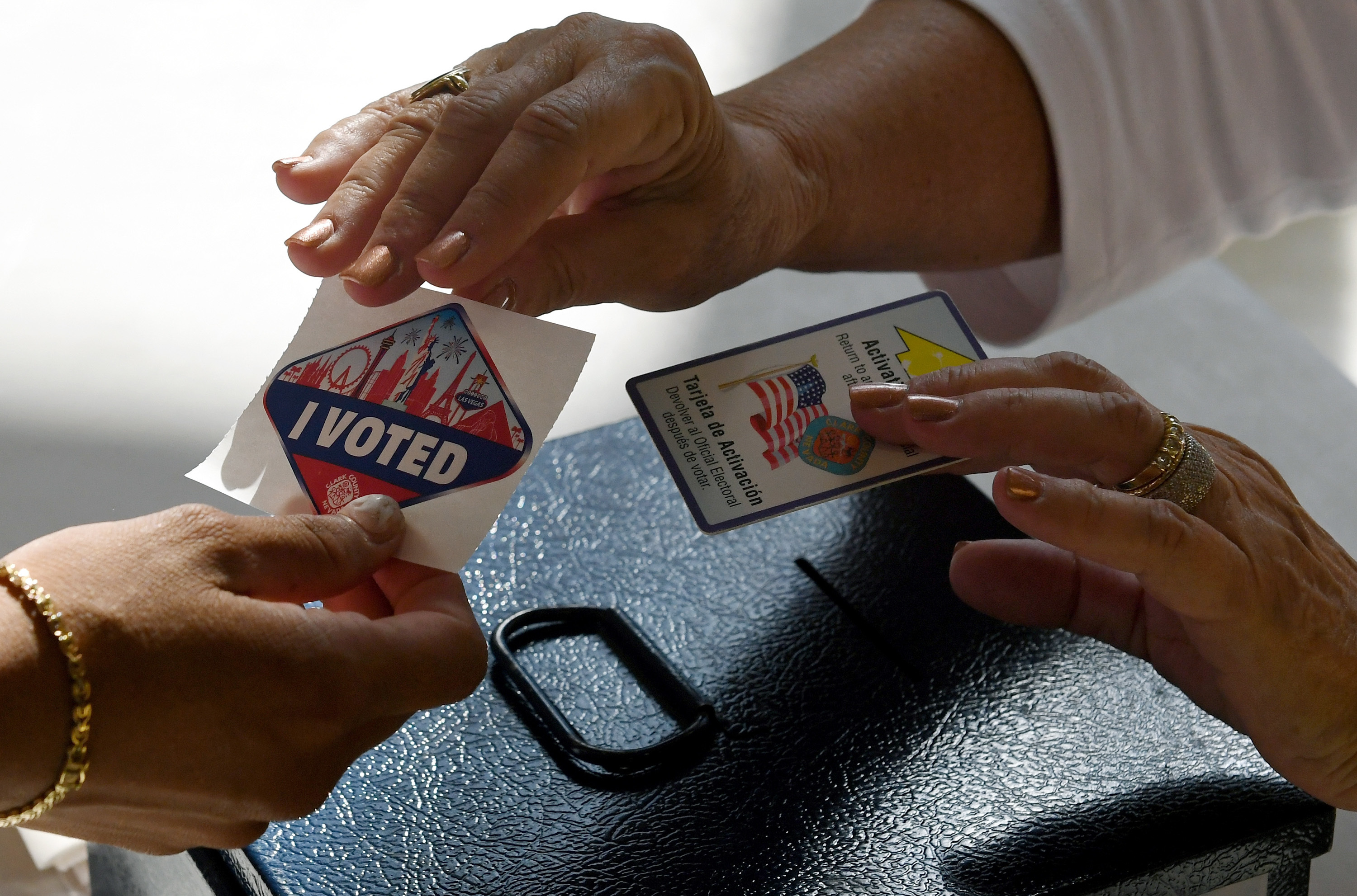 A poll worker hands out a Las Vegas Strip-themed "I Voted" sticker after taking back her voter activation card on Nov. 8, 2016, in Nevada. A White House panel that is looking into voter fraud allegations wants names, addresses, birthdates, party affiliation and elections voted in since 2006 for every registered voter in the country.