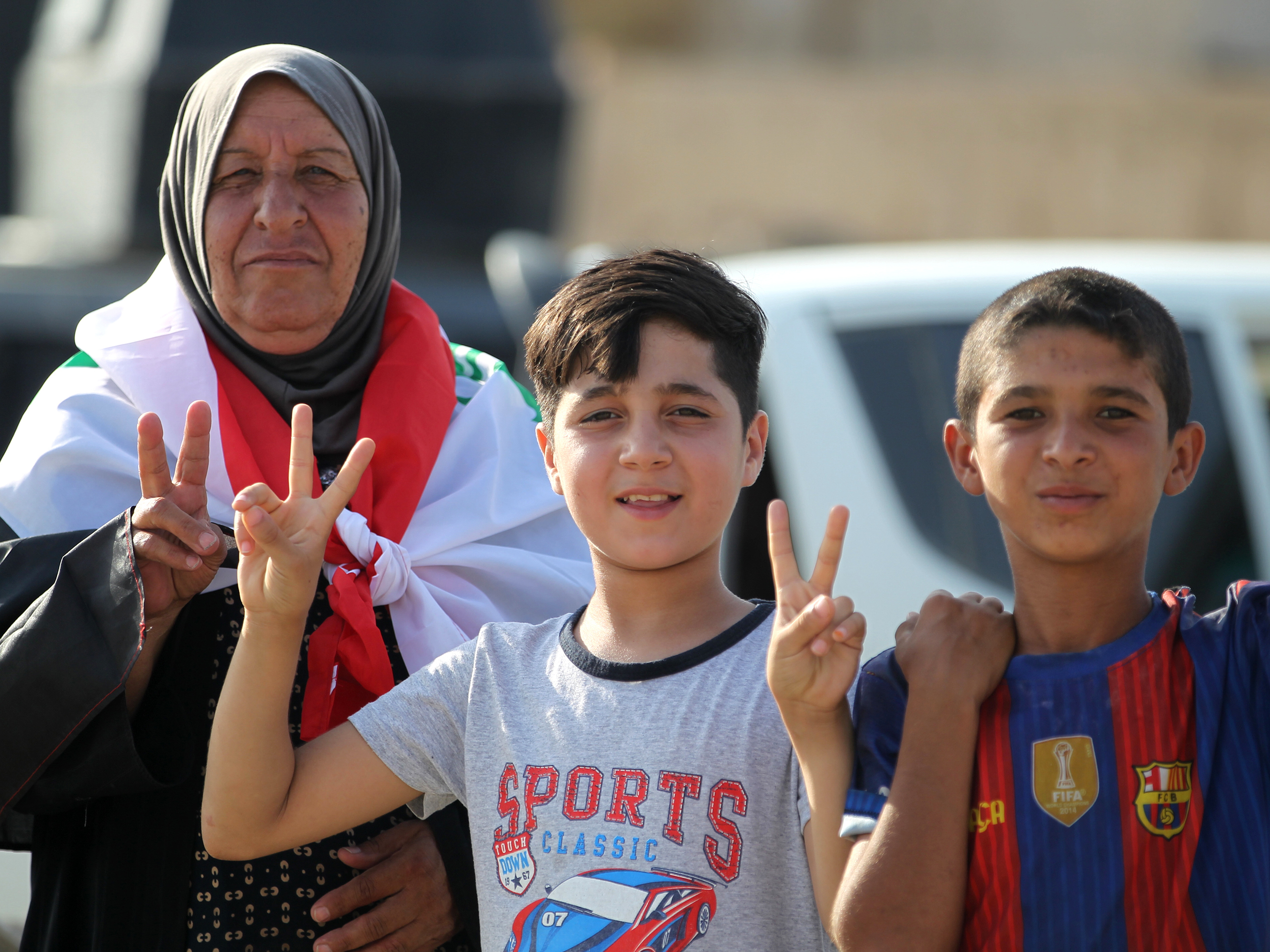 Iraqi civilians in Mosul's Old City flash the "victory" sign as they celebrate the government's announcement of the "liberation" of the embattled city Sunday.
