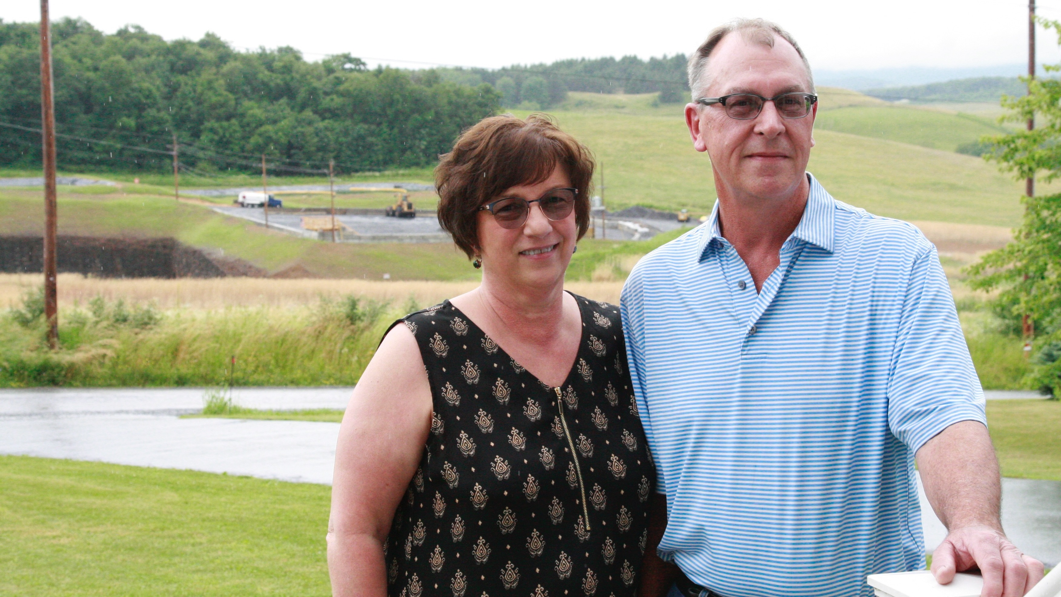 Mary Jo and Mike Picklo stand in their front yard in Somerset County, Pa. Behind them is the Acosta Deep Mine. (NPR)