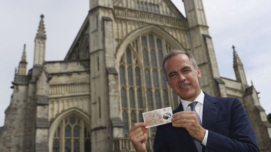 The Governor of the Bank of England, Mark Carney, poses at Winchester Cathedral in England on Tuesday, with the new 10-pound note featuring the image of Jane Austen. Two hundred years to the day since Jane Austen was laid to rest at Winchester's grand cathedral, the bank unveiled a new 10-pound note featuring the beloved author. (Steve Parsons/AP)