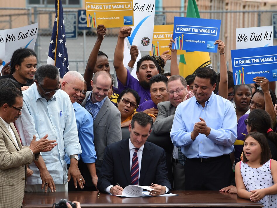 In 2015, Los Angeles Mayor Eric Garcetti (center) signs into law an ordinance raising the city's minimum wage to $15 an hour by 2020. Though California isn't one of them, 27 states have passed laws requiring cities to abide by state minimums. (Mark Ralston/AFP/Getty Images)