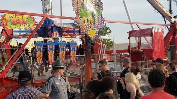People watch as authorities respond near the Fire Ball ride after it part of it broke off while in motion Wednesday night at the Ohio State Fair in Columbus, Ohio. One person was killed and several were critically injured.