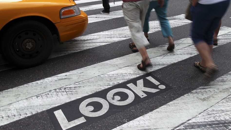Pedestrians walk past a "Look!" sign on the crosswalk at the intersection of 42nd Street and Second Avenue in New York. Cities all over the country are looking for ways to get pedestrians to pay more attention. (Seth Wenig/AP)