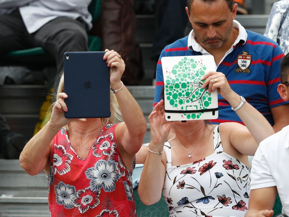 A spectator at Wimbledon last month uses an iPad to take pictures of the action. Improved sales of the tablets were part of the good news out of Apple's quarterly report. (Adrian Dennis/AFP/Getty Images)
