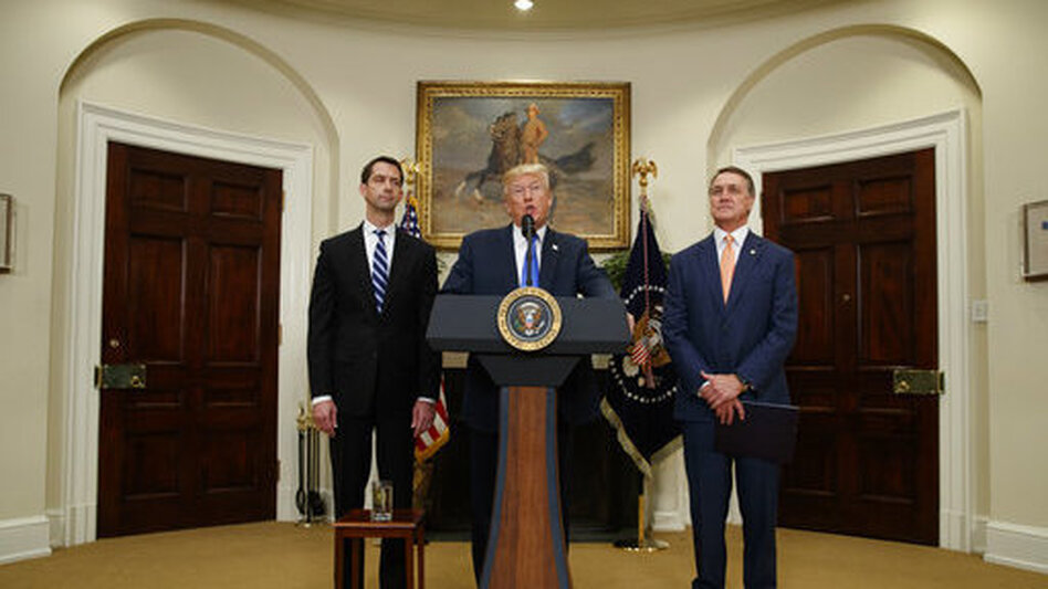 President Trump, flanked by Sens. Tom Cotton, R-Ark. (left), and David Perdue, R-Ga., speaks in the Roosevelt Room of the White House on Wednesday during the unveiling of legislation that would place new limits on legal immigration. (Evan Vucci/AP)