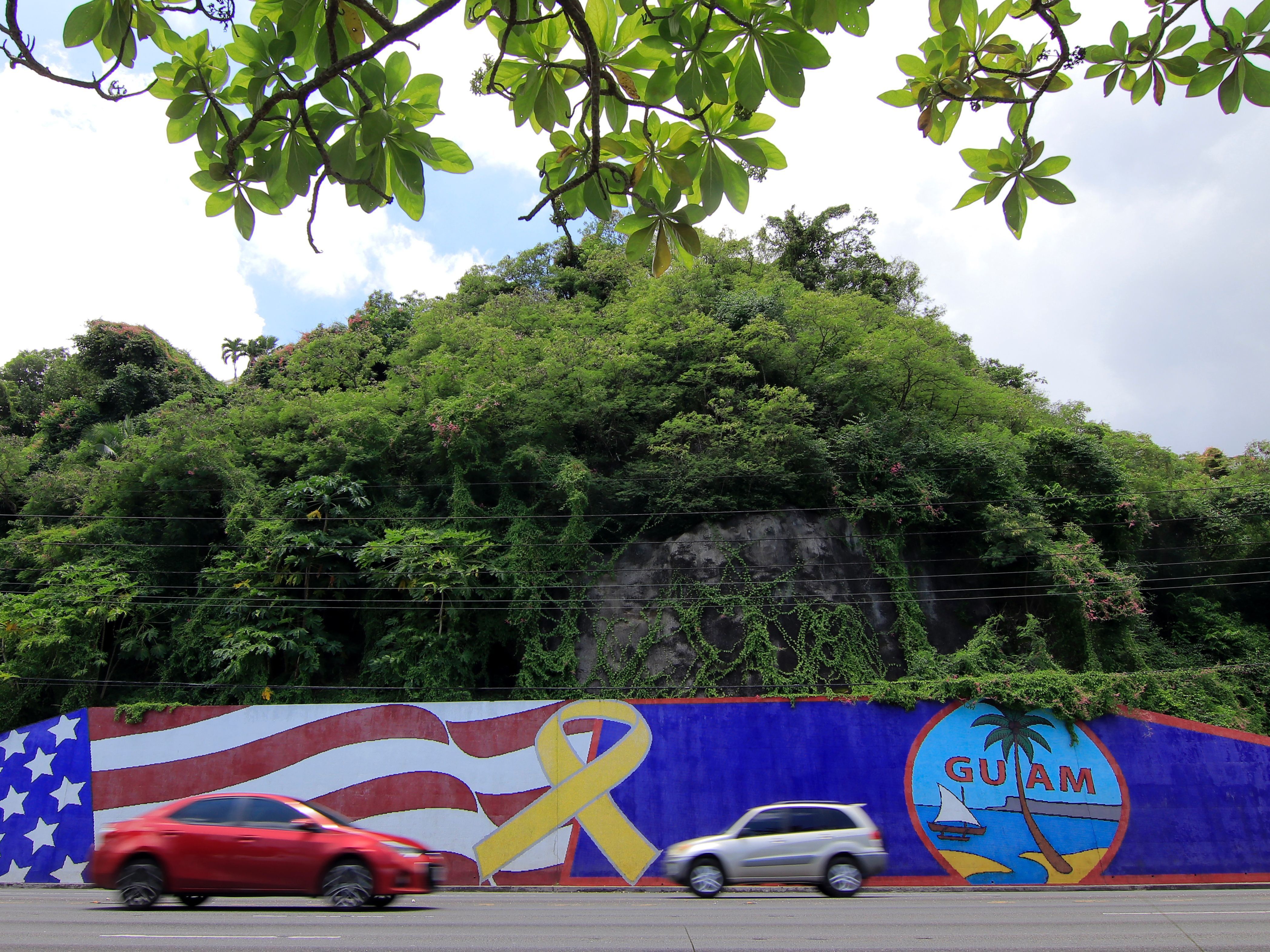 Afternoon traffic passes in front of a wall painted with the flags of the U.S. and Guam in the Tumon district on the island of Guam on Friday. The island has become a talking point in the rhetoric coming from President Trump and North Korea. (AFP/Getty Images)