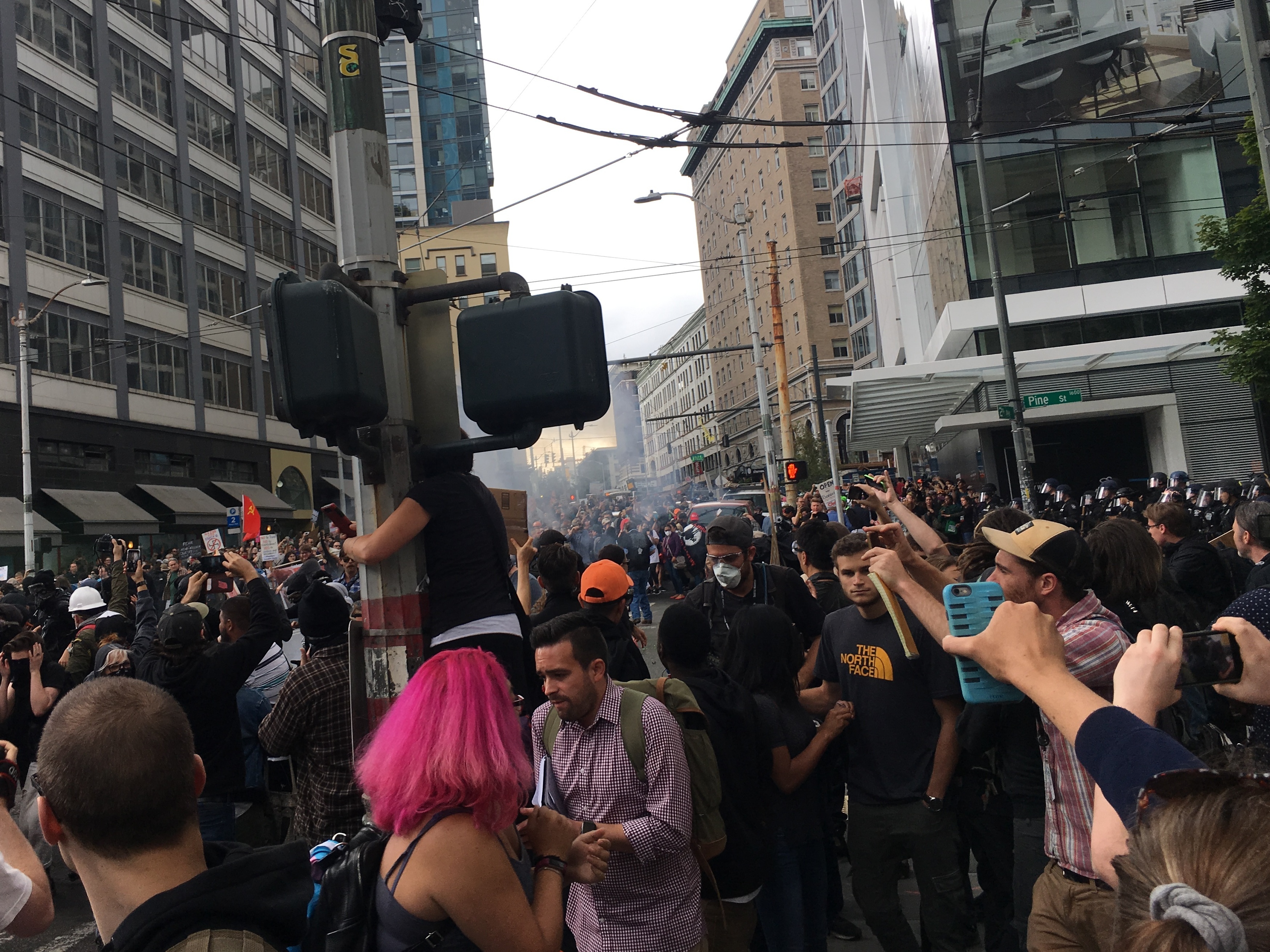 Demonstrators in Seattle scatter after hearing a loud bang, apparently from a police riot control device. Protesters who had gathered to counter a pro-Trump rally Sunday had a tense standoff with local police, who sought to keep the two groups separate. (KNKX)