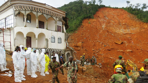 Search and rescue team members and soldiers work near a mudslide site and a damaged building near Freetown, Sierra Leone, on Tuesday.