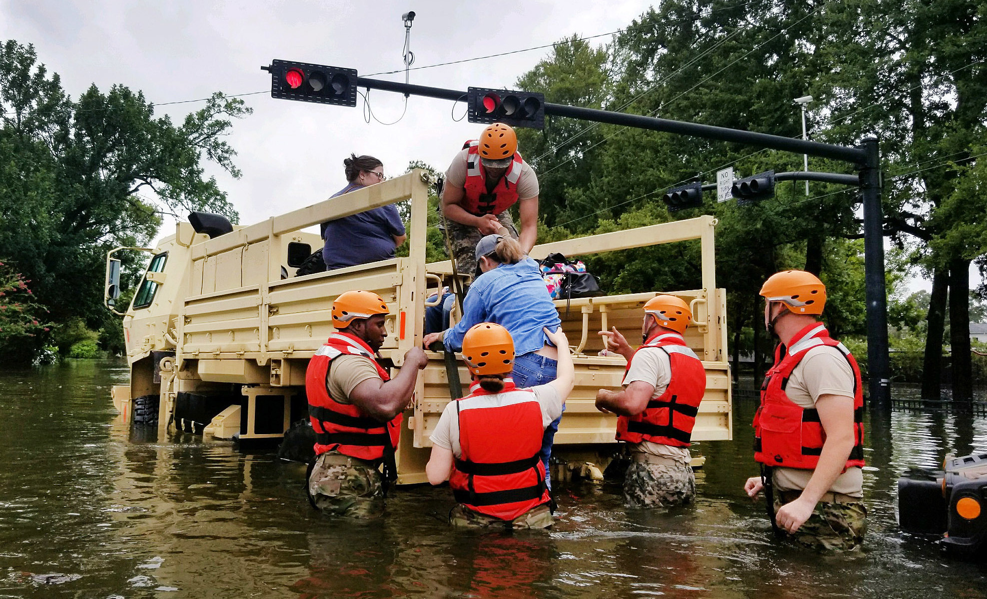 Texas National Guardsmen assist residents affected by flooding onto a military vehicle on Sunday in Houston. (Army National Guard via Getty Images)