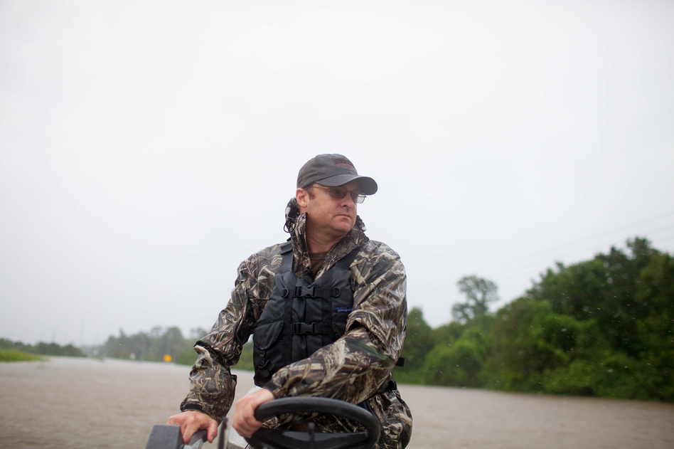 Troy King navigates his boat through a flooded portion of Highway 90 in Houston on his way to rescue the Galvan family. (Katie Hayes Luke for NPR)