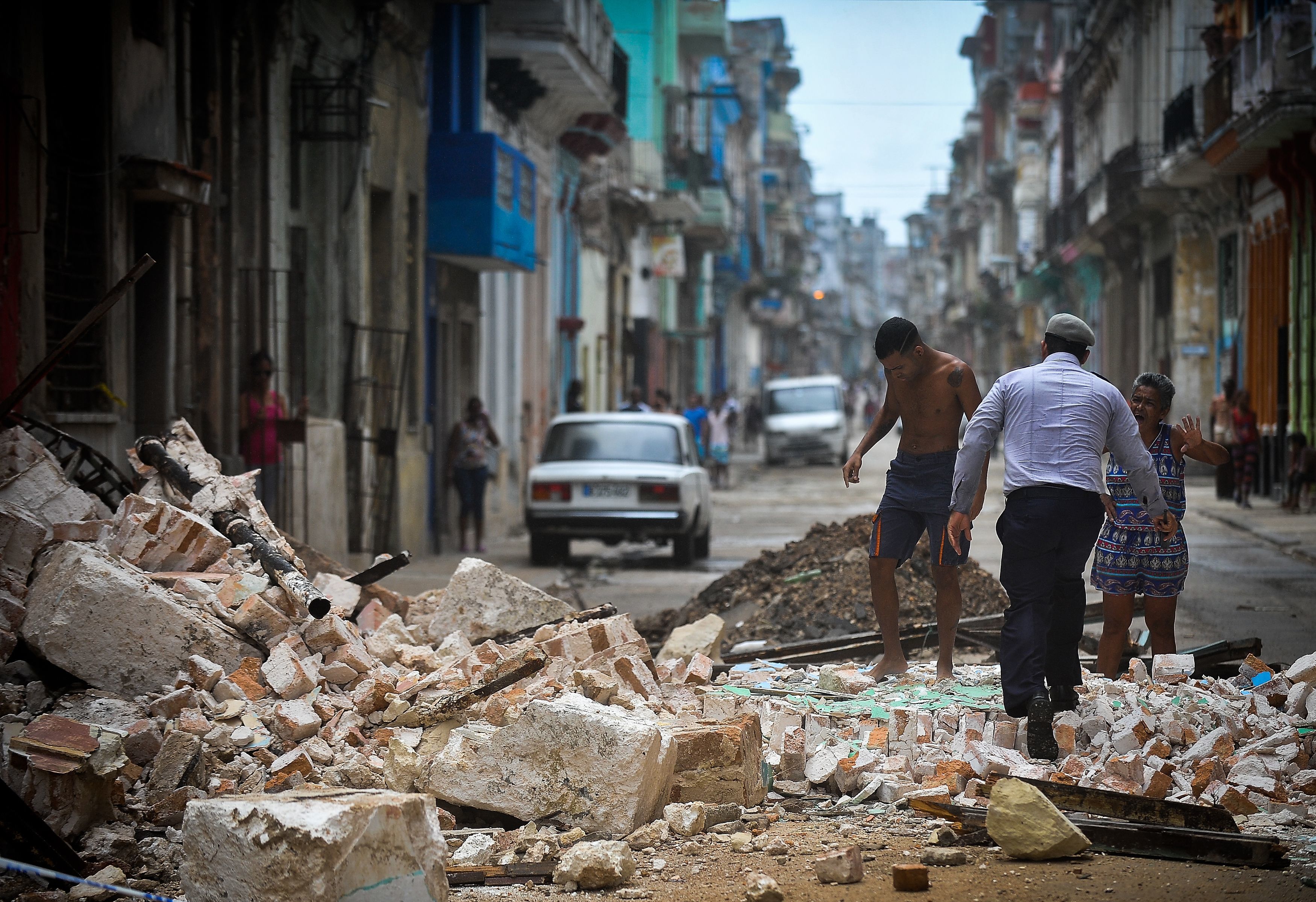 Cubans wade through the rubble from a collapsed building in Havana, on Saturday. The Cuban government extended its maximum state of alert to three additional provinces, including Havana, amid fears of flooding in low-lying areas.