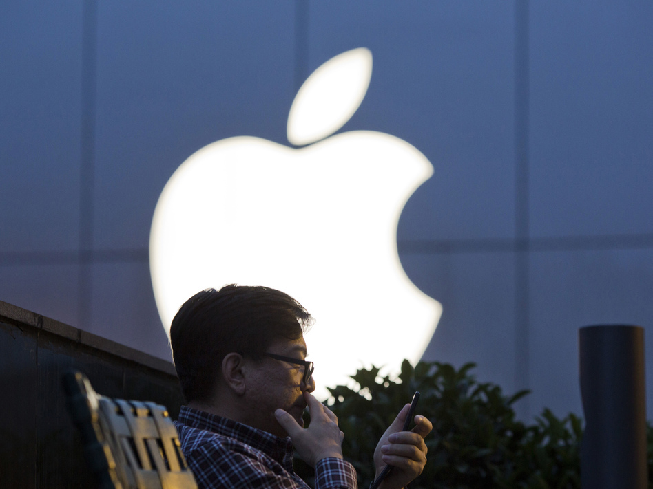 A man uses his mobile phone near an Apple store logo in Beijing. The latest iPhone is expected to include facial recognition as an unlocking feature but do away with the home button. (Ng Han Guan/AP)