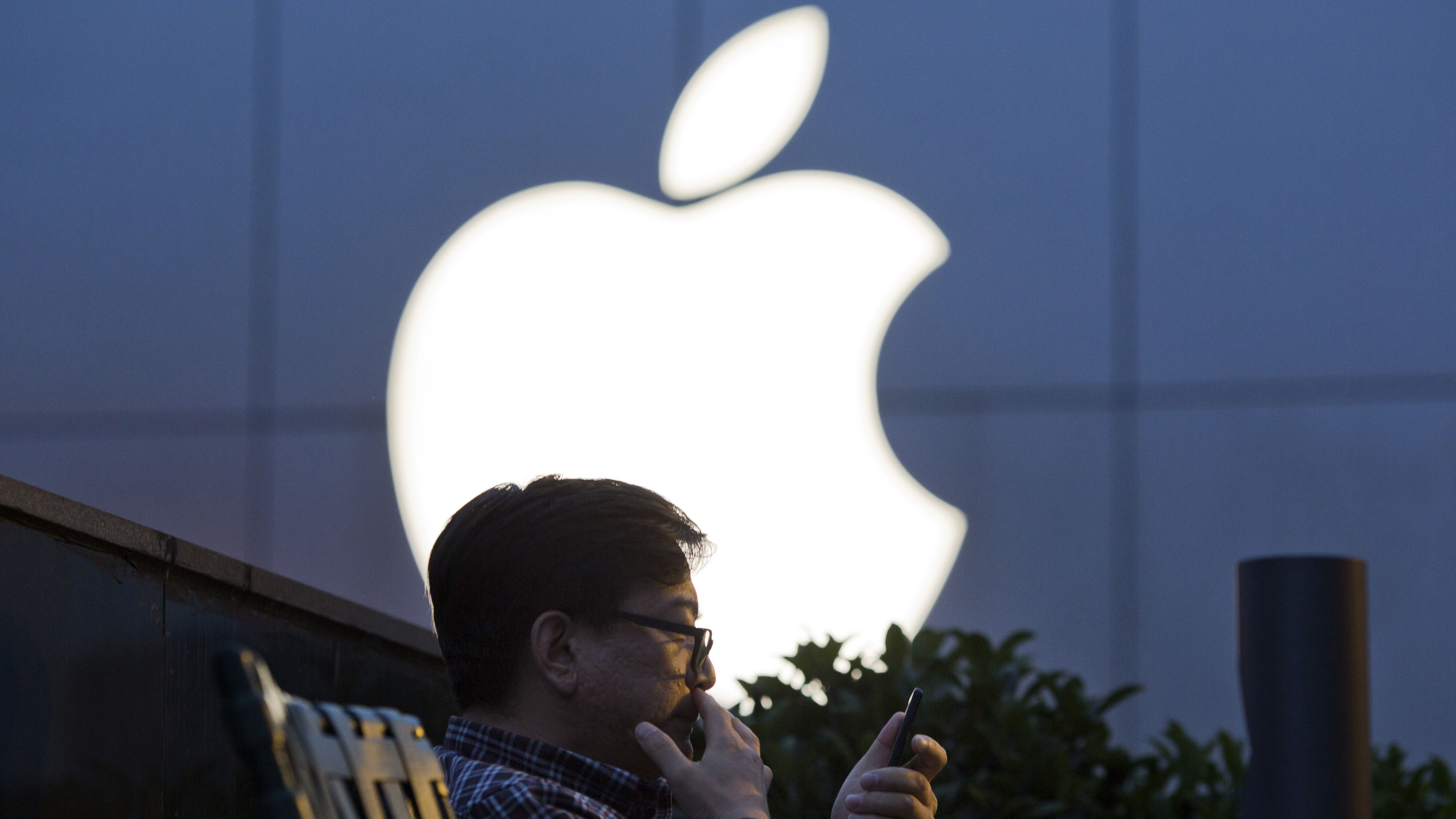 A man uses his mobile phone near an Apple store logo in Beijing. The latest iPhone is expected to include facial recognition as an unlocking feature but do away with the home button.