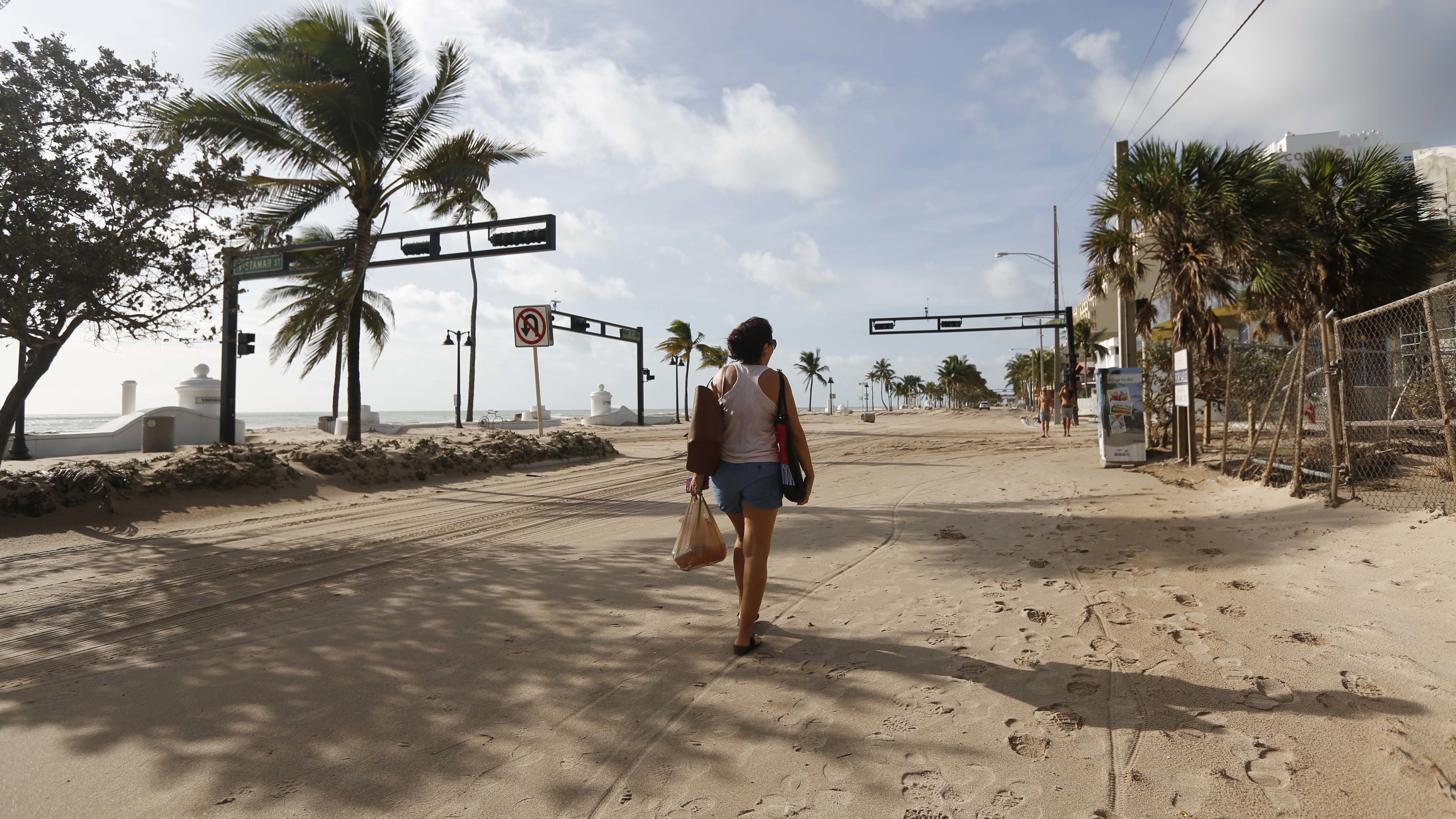 Hurricane Irma dumped water on towns and covered oceanside streets with sand in several states. Here, Amela Desanto walks on the sand-covered road along Fort Lauderdale Beach on Monday, as the storm headed inland. (For The Washington Post/Getty Images)