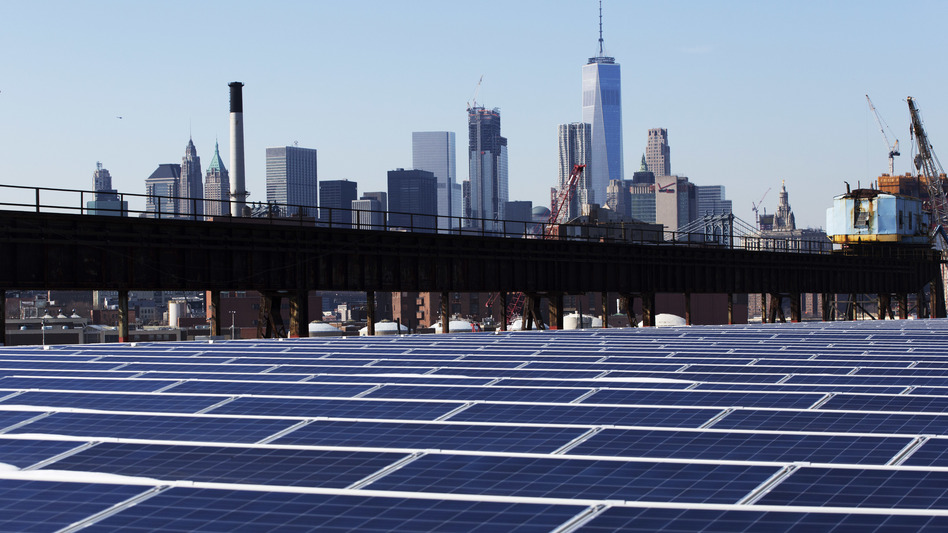 U.S. regulators say cheap solar panels from China have hurt U.S. manufacturers. Here, the Manhattan skyline is seen beyond a rooftop covered with solar panels. (Mark Lennihan/AP)