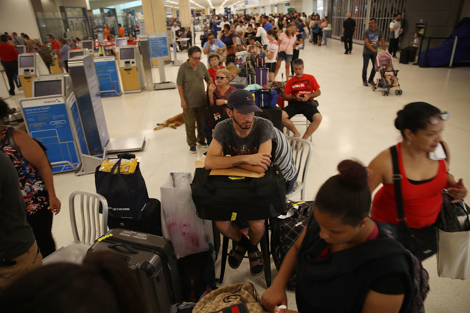Edgar Algarin (center) and others wait in line to get a flight at the Luis Muñoz Marín International Airport in San Juan, Puerto Rico, on Monday. Hurricane Maria has left the island without power and with dwindling supplies of food and fuel. (Joe Raedle/Getty Images)