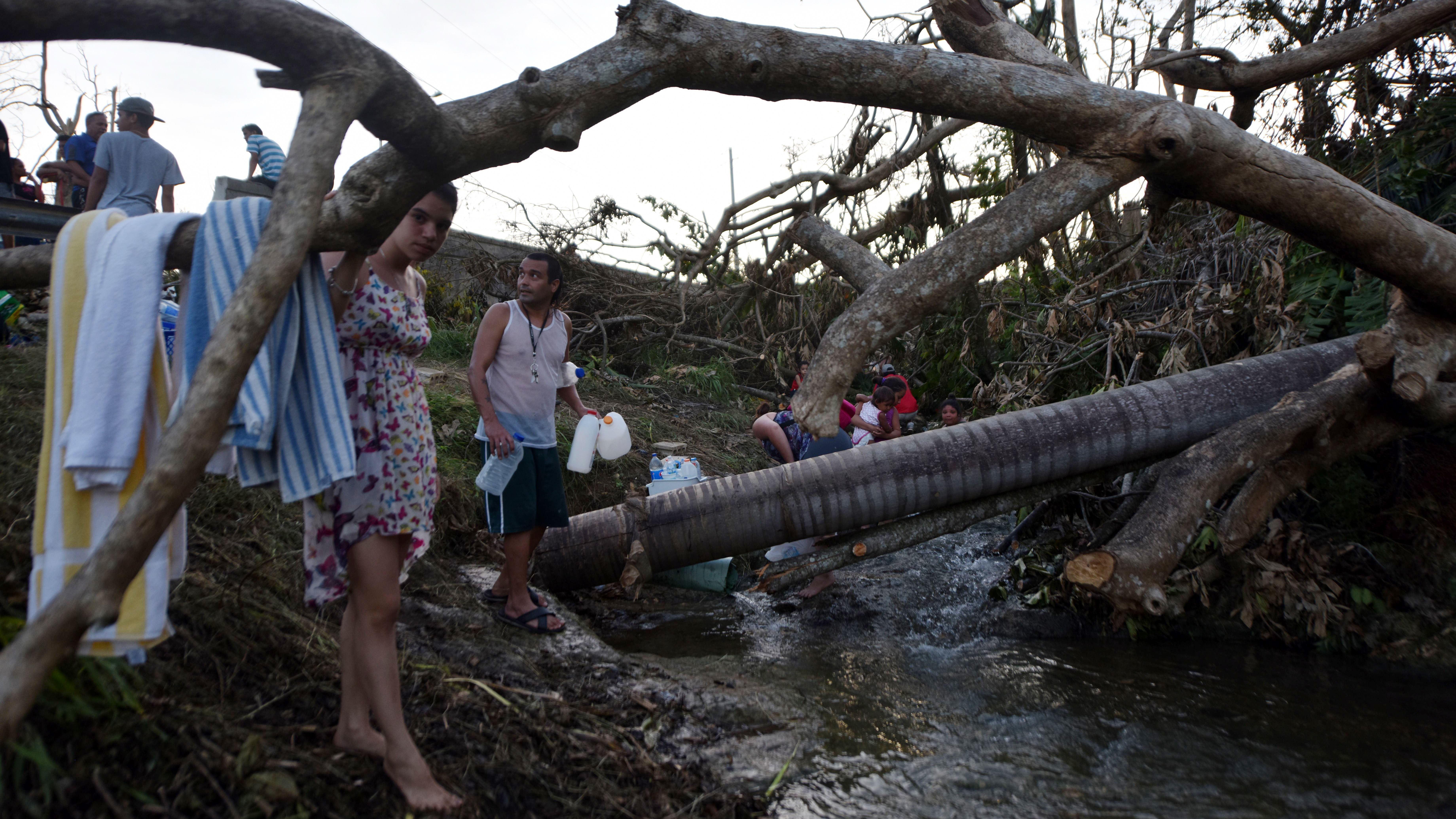 People carry water in bottles retrieved from a canal due to lack of water after Hurricane Maria, in Toa Alta, Puerto Rico, on Monday. (AFP/Getty Images)