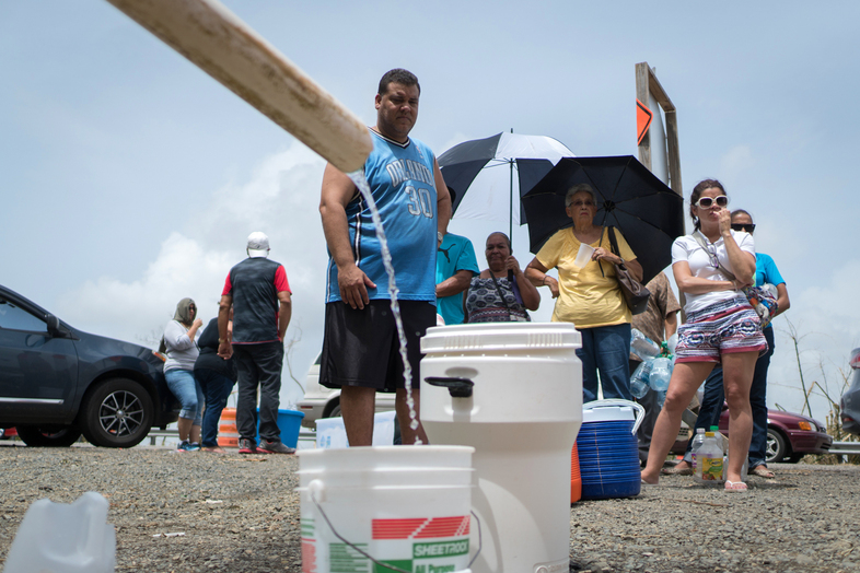 People fill containers with water from a stream near the Puerto Rico Highway 52 in Cayey on Tuesday. People have been without water service in their homes after Hurricane Maria roared through a week ago. (Angel Valentin for NPR)
