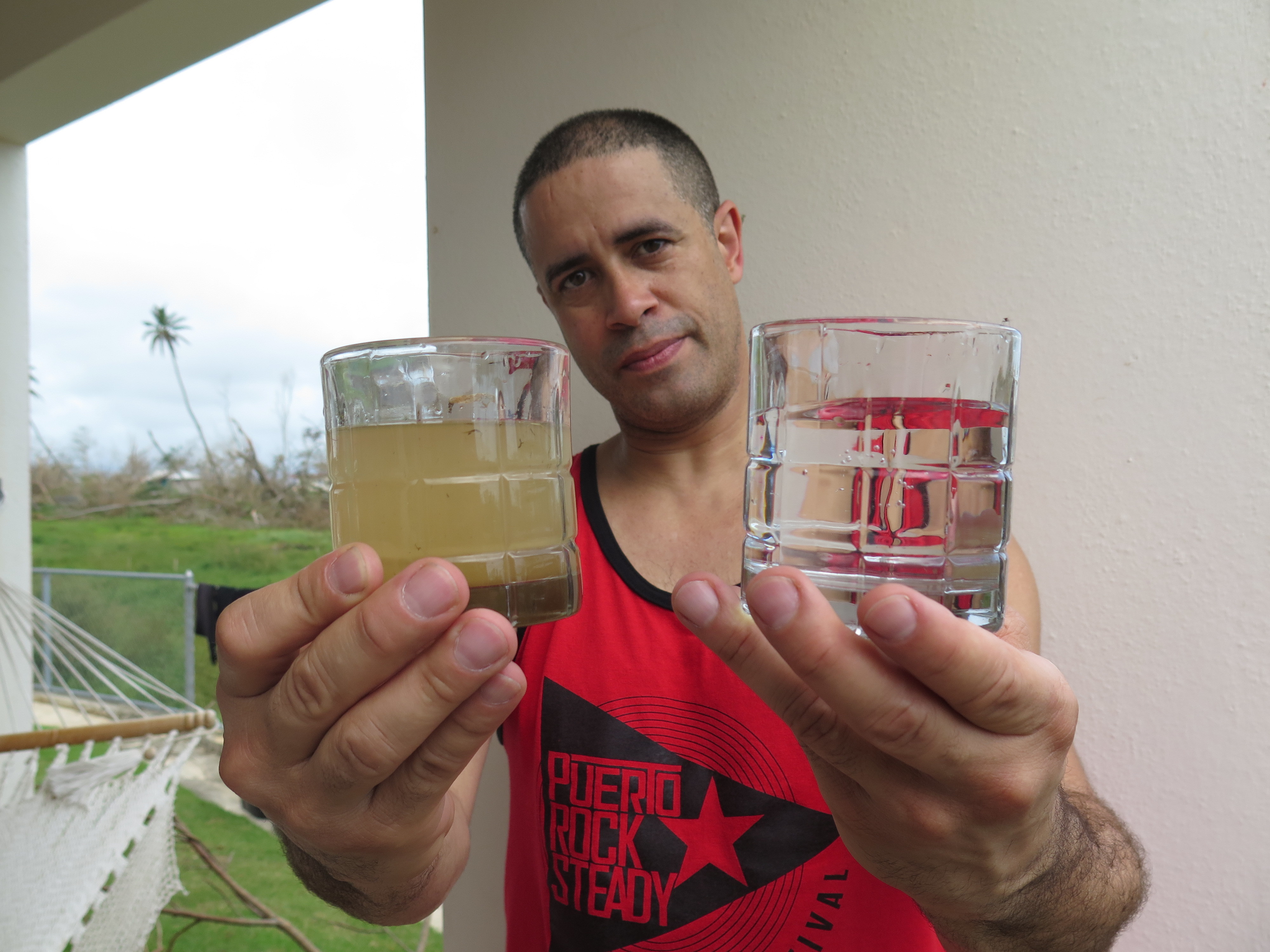 Richard Colón, better known by his stage name Crazy Legs at his home in Isabela, Puerto Rico, shows the before-and-after of the water filtration system he's helping deliver to people in remote areas. (NPR)