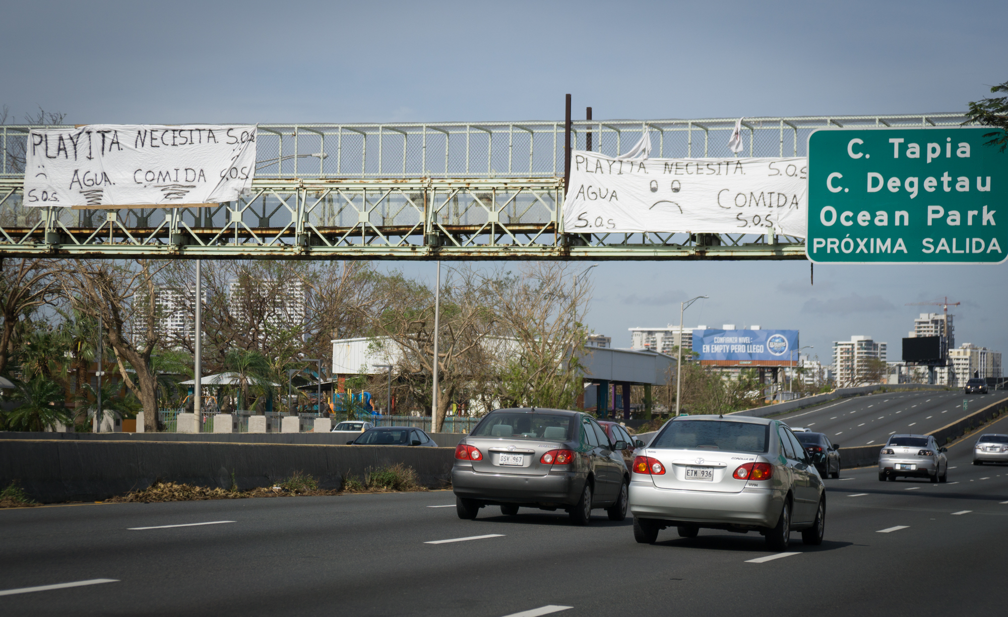 A pair of SOS signs hang from a pedestrian overpass in the San Juan's Playita neighborhood asking for food and water following Hurricane Maria's destruction in Puerto Rico. (Angel Valentin for NPR)