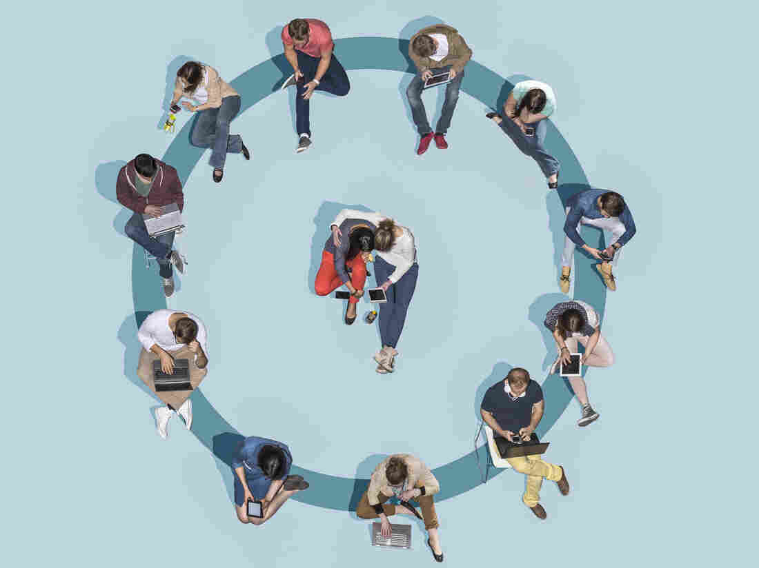 Group of young people using technologies sitting on a blue circle