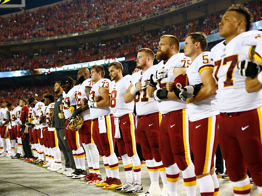 The Washington, D.C., football team stands at attention while linked in arms during the national anthem before Monday night's game against the Kansas City Chiefs at Arrowhead Stadium in Kansas City, Mo. (Getty Images)
