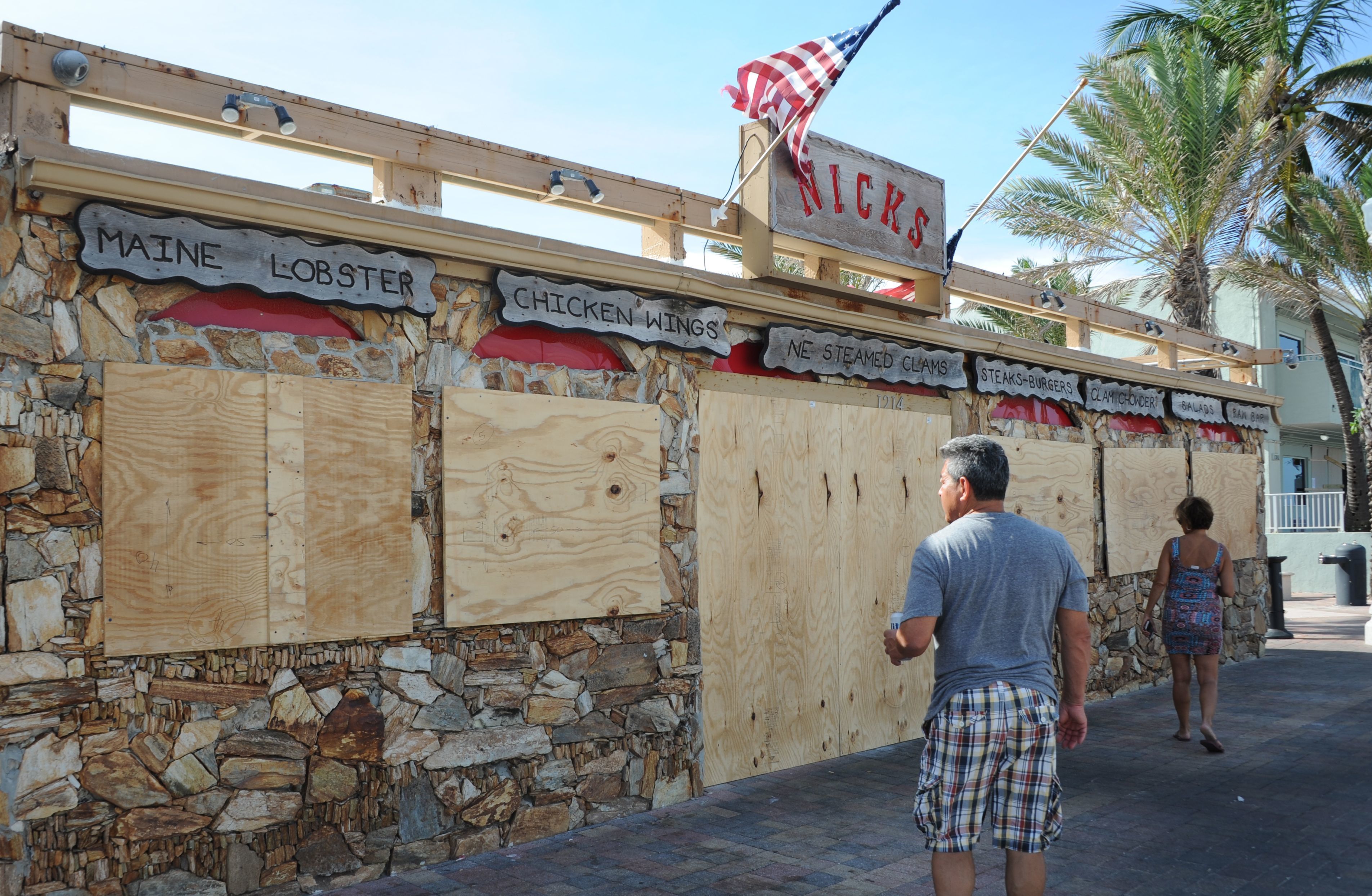 Tourists walk past a restaurant, closed in preparation for hurricane Irma, in Fort Lauderdale, Fla., on Sept. 7. The Bureau of Labor Statistics says a drop in U.S. jobs in September was likely reflecting the impact of hurricanes on workers — particularly restaurant employees who aren't paid if they aren't on the job. (AFP/Getty Images)