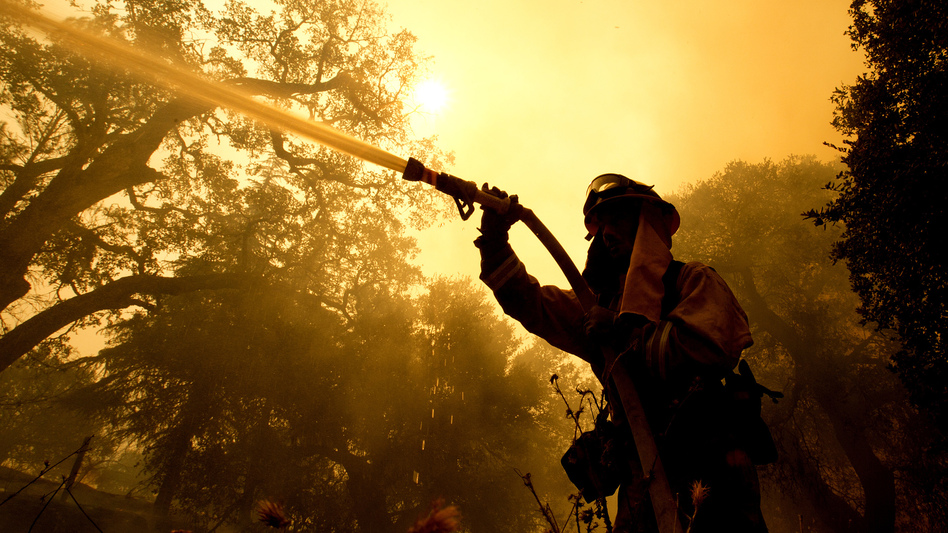 Napa County firefighter Jason Sheumann sprays water on a home as he battles flames from a wildfire on Monday in Napa, Calif. Wildfires whipped by powerful winds swept through Northern California sending residents on a headlong flight to safety through smoke and flames as homes burned. (Rich Pedroncelli/AP)