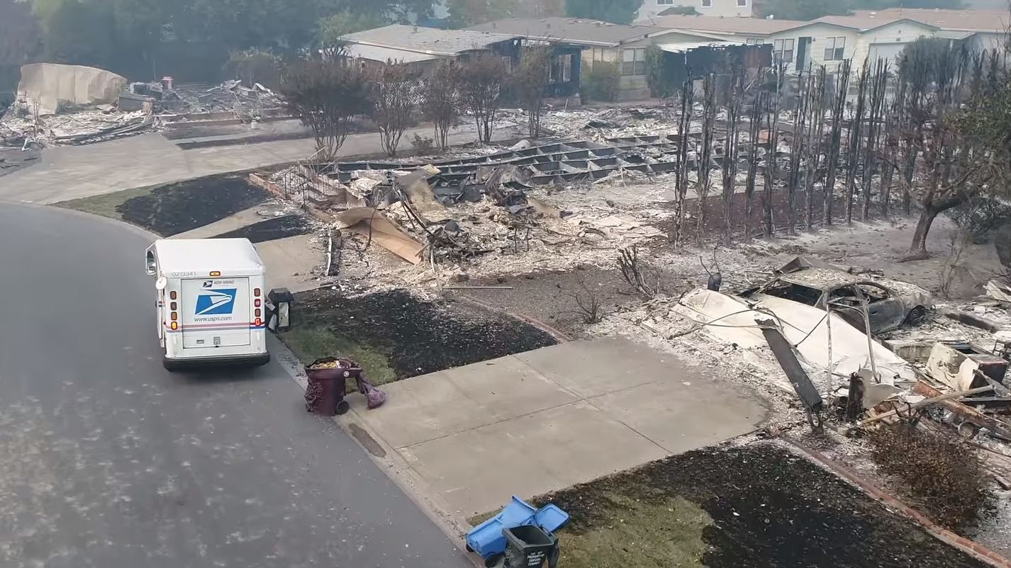 Aerial drone footage shows a U.S. Postal Service mail carrier making the rounds in Santa Rosa, Calif., delivering mail at houses that were reduced to rubble by intense wildfires. (Douglas Thron via YouTube)