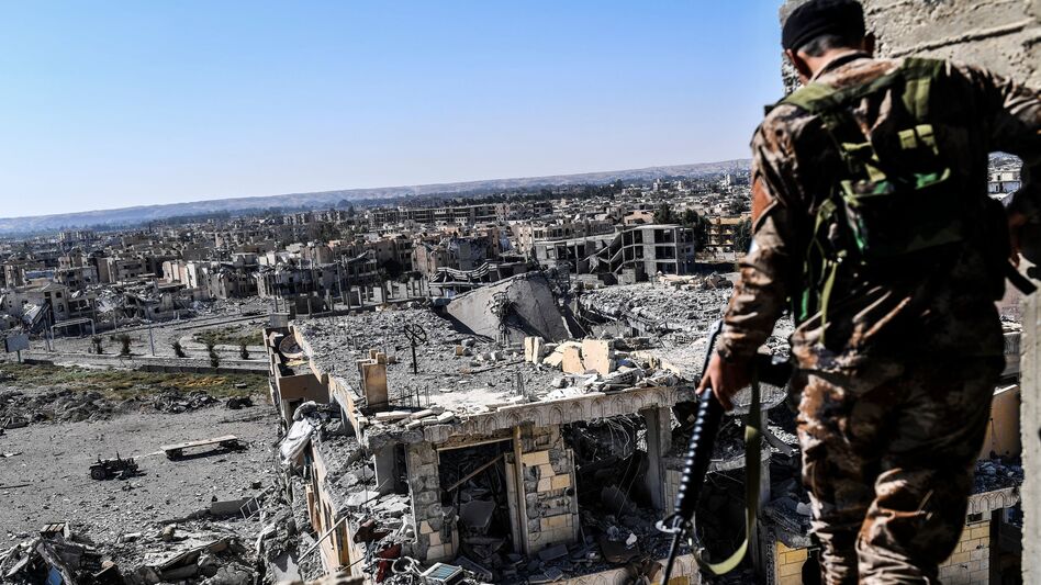 A member of the Syrian Democratic Forces walks on a building near Raqqa's stadium Monday, as they cleared the last positions on the front line in the fight against ISIS. (Bulent Kilic/AFP/Getty Images)
