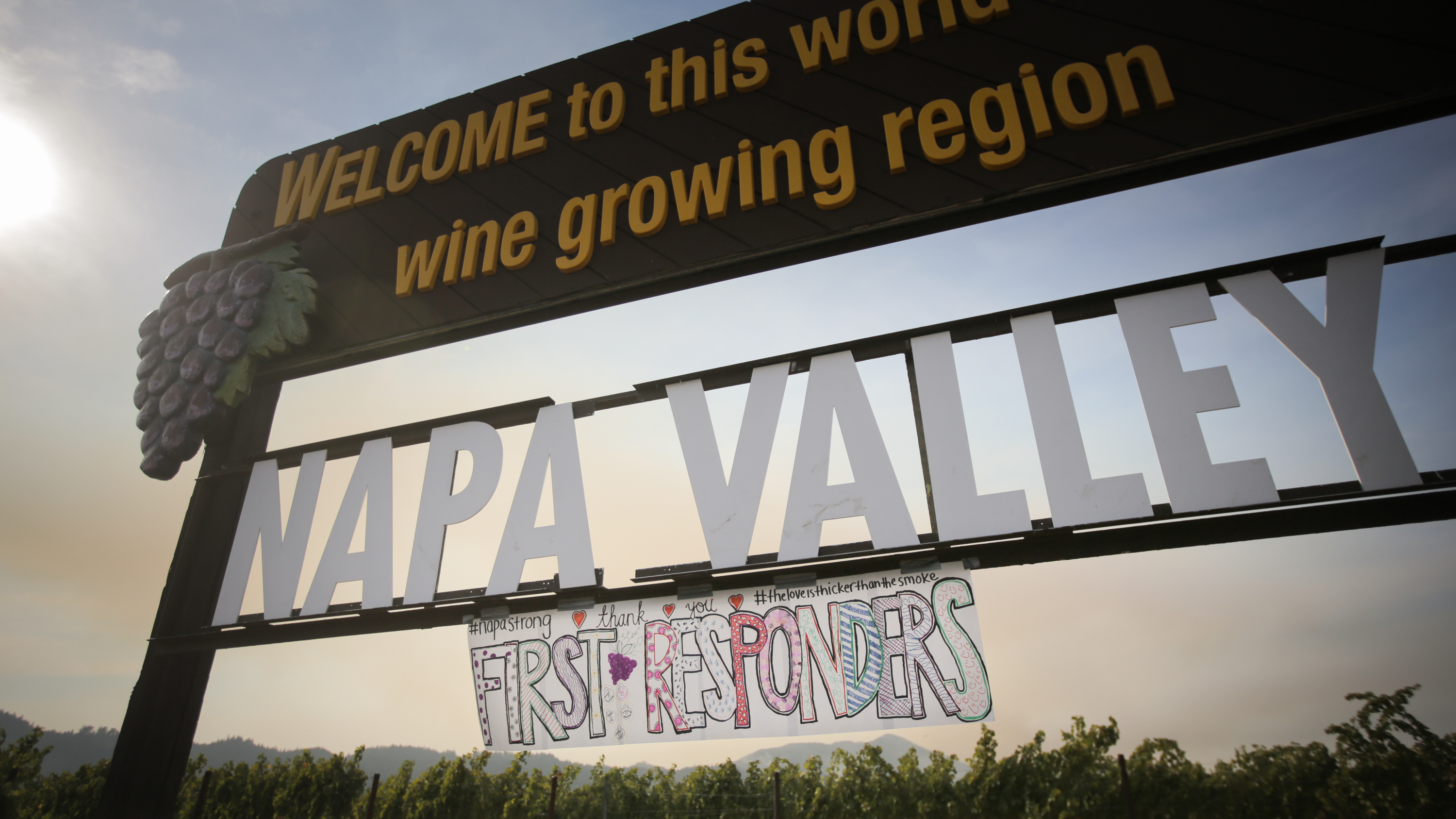A handmade sign is seen attached to the Napa Valley welcome sign on Oct. 16, 2017 in Oakville, Calif. At least 40 people are confirmed dead, dozens are still missing, and at least 5,700 buildings have been destroyed since wildfires broke out a week ago. (Getty Images)