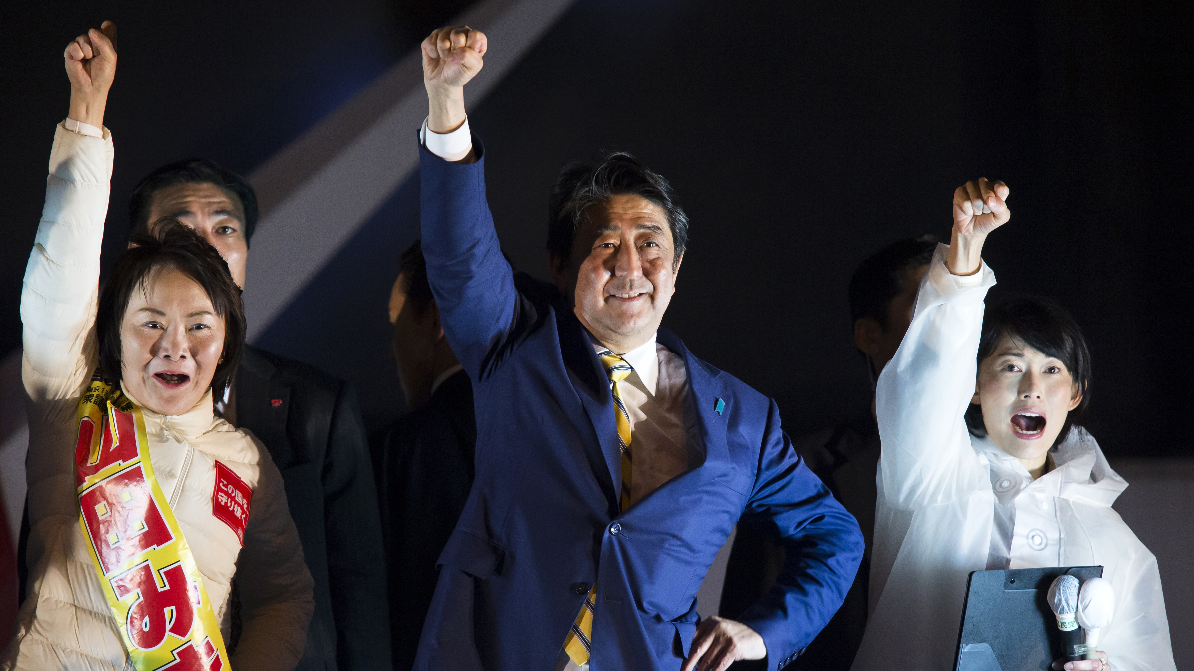 Shinzo Abe, Japan's prime minister and president of the Liberal Democratic Party (LDP), center, raises his arm during an election campaign rally in Tokyo, on Saturday. Exit polls show the LDP winning a majority of parliament seats in Sunday's election. (Bloomberg via Getty Images)