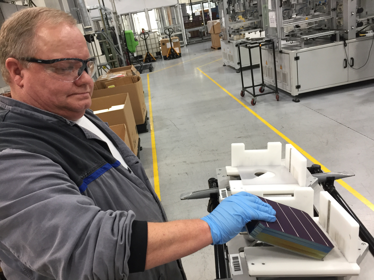 At the SolarWorld manufacturing plant in Hillsboro, Ore., John Clason stacks solar cells before loading them into machines that build solar panels. (Oregon Public Broadcasting)