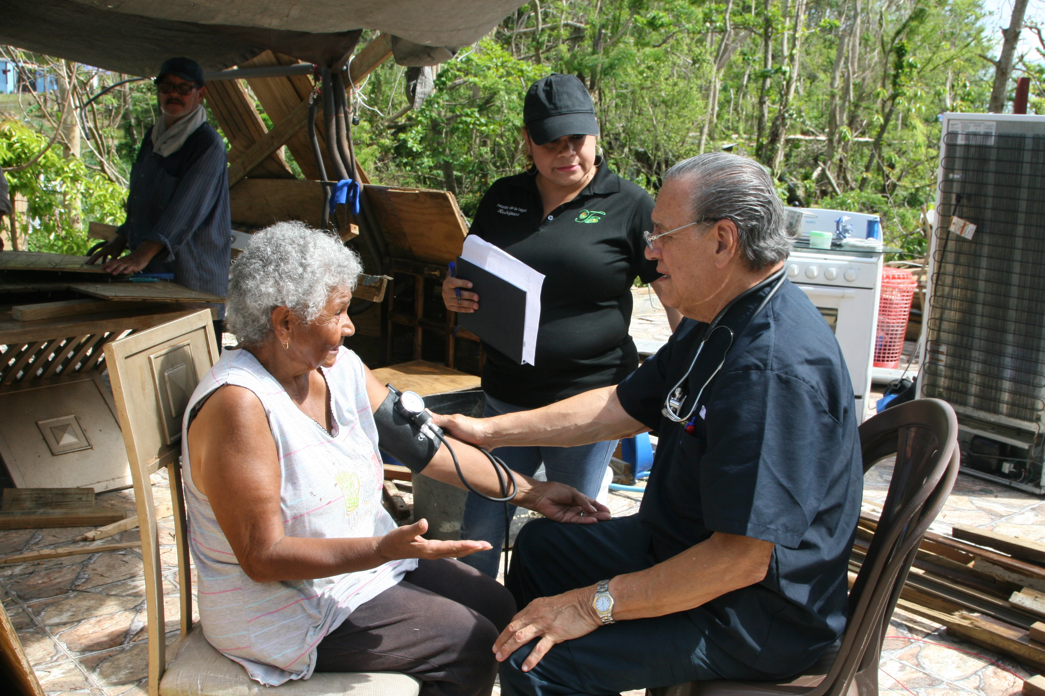Dr. Eduardo Ibarra checks the blood pressure of Carmen Garcia Lavoy in the Toa Baja area of Puerto Rico. He's been making house calls in the area with nurse Erika Rodriguez. (NPR)