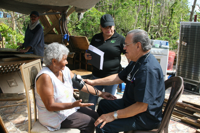 Dr. Eduardo Ibarra checks the blood pressure of Carmen Garcia Lavoy in the Toa Baja area of Puerto Rico. He's been making house calls in the area with nurse Erika Rodriguez. (Jason Beaubien/NPR )