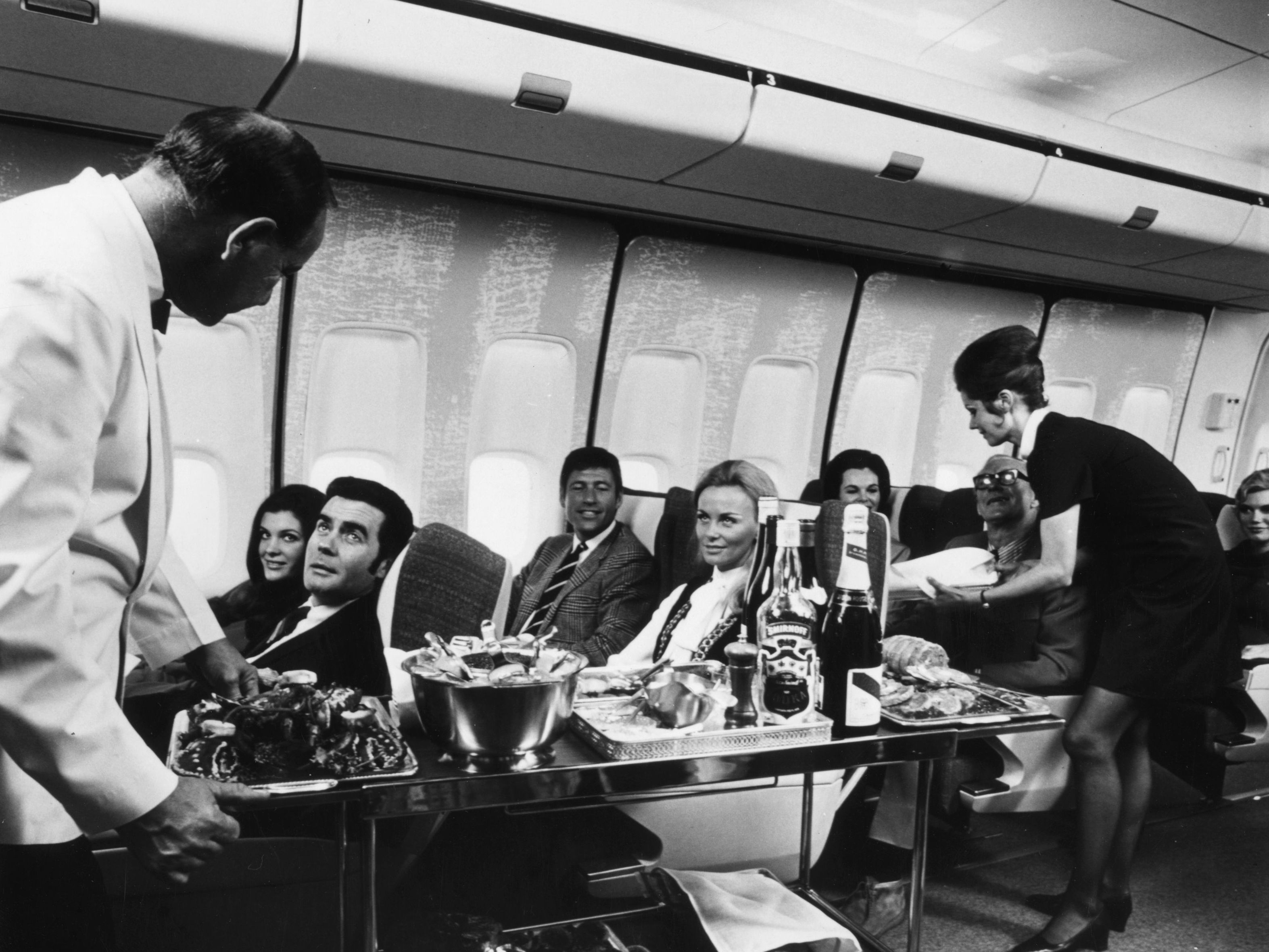 A steward and stewardess serving first-class passengers with drinks and refreshments on board a Boeing 747 in 1970. (Getty Images)
