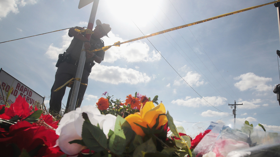 A police officer ties off crime scene tape near a small memorial close to the First Baptist Church of Sutherland Springs on Tuesday in Sutherland Springs, Texas. On Sunday, a gunman, Devin Patrick Kelley, killed 26 people at the church and wounded 20 more when he opened fire during a Sunday service. (Scott Olson/Getty Images)