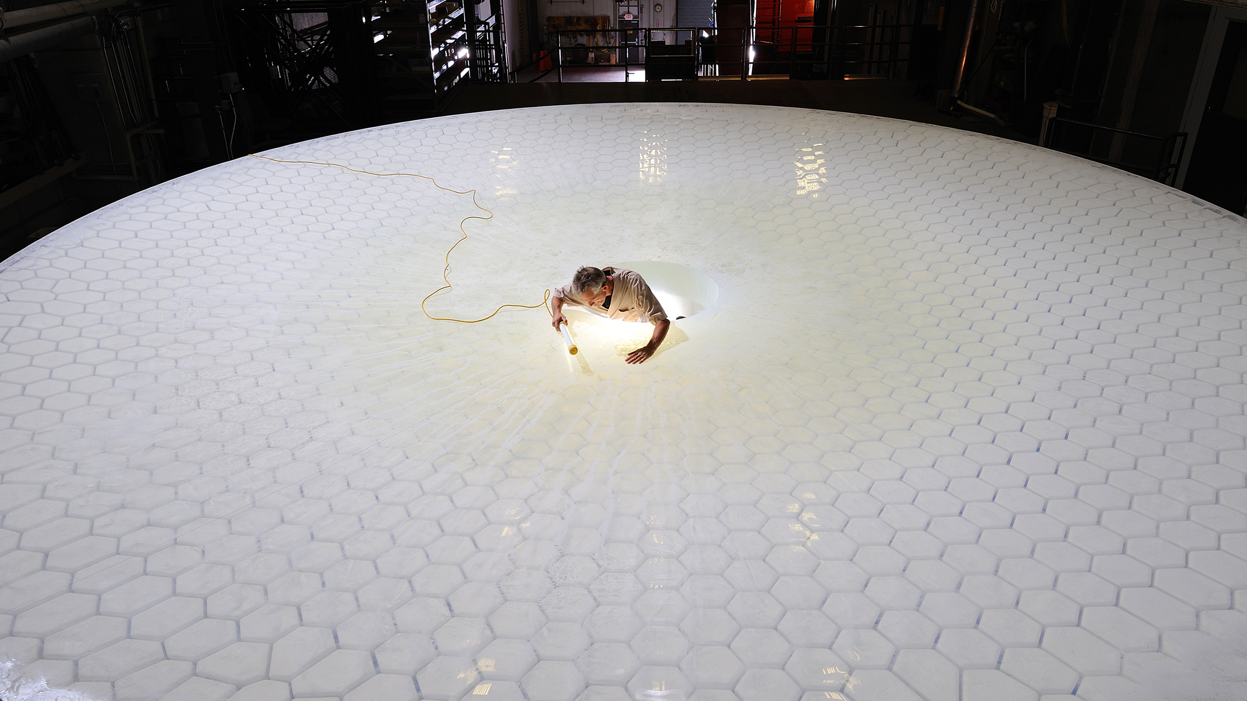 A technician examines the mirror on the Large Synoptic Survey Telescope. Scientists at two national laboratories are currently building the components for an enormous digital camera that will capture images from the telescope.