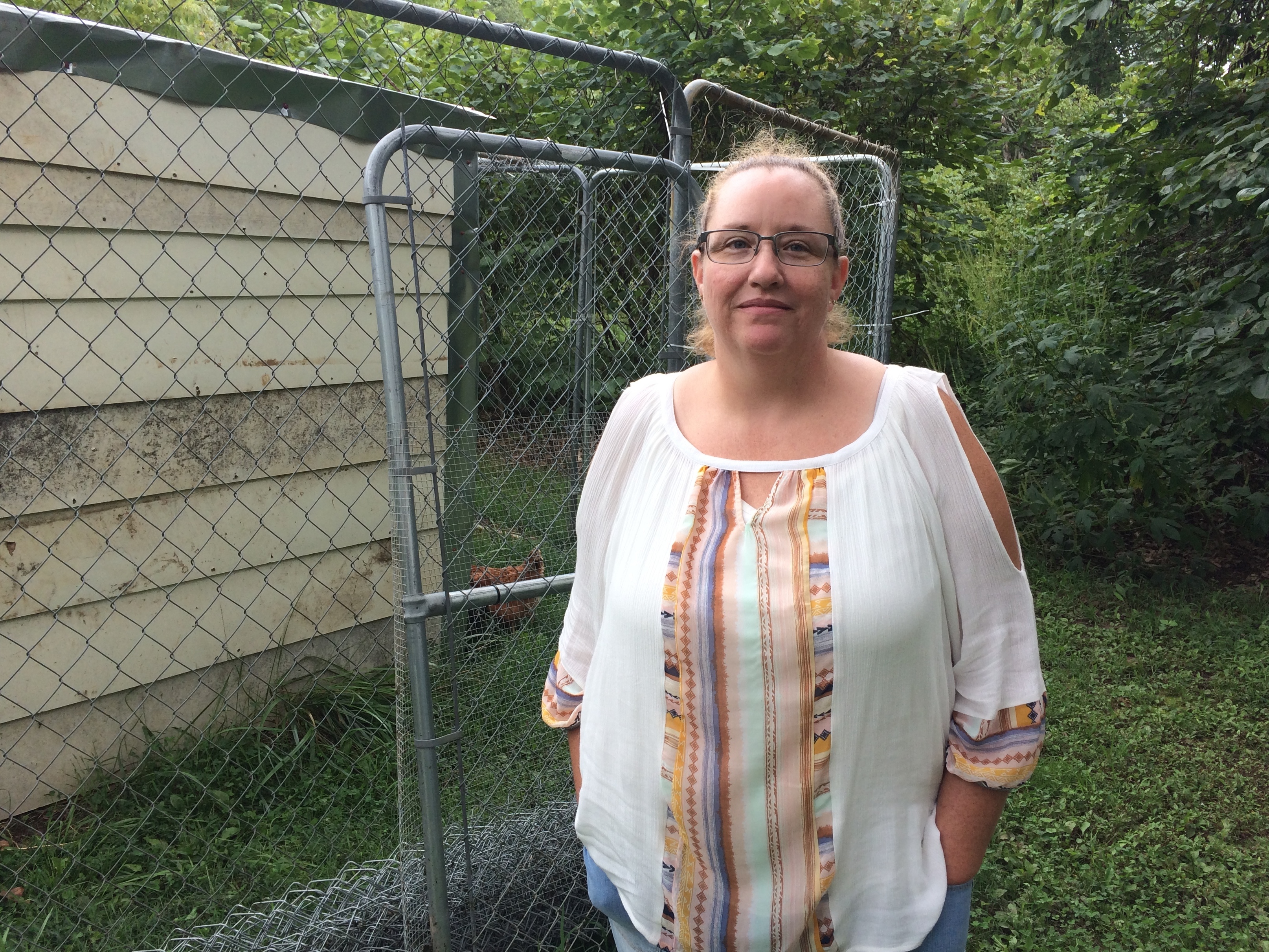 Medical debts weigh on Geneva Wilson, who keeps a chicken and rooster in a coop behind her cabin in rural southwest Missouri. (Alex Smith/KCUR 89.3)
