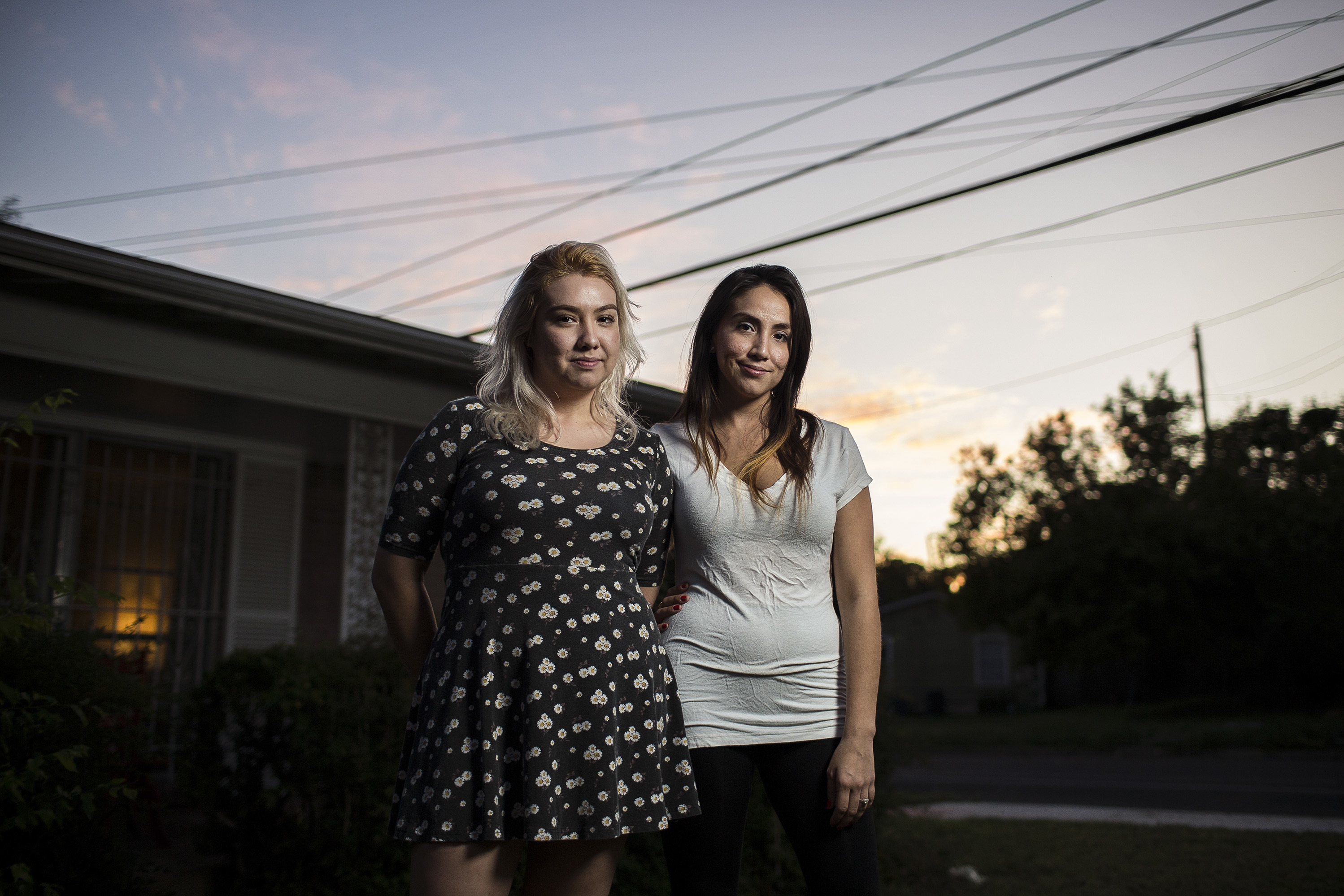 Sisters Andrea and Claudia De La Vega stand in the yard of their home in Austin. (KUT)