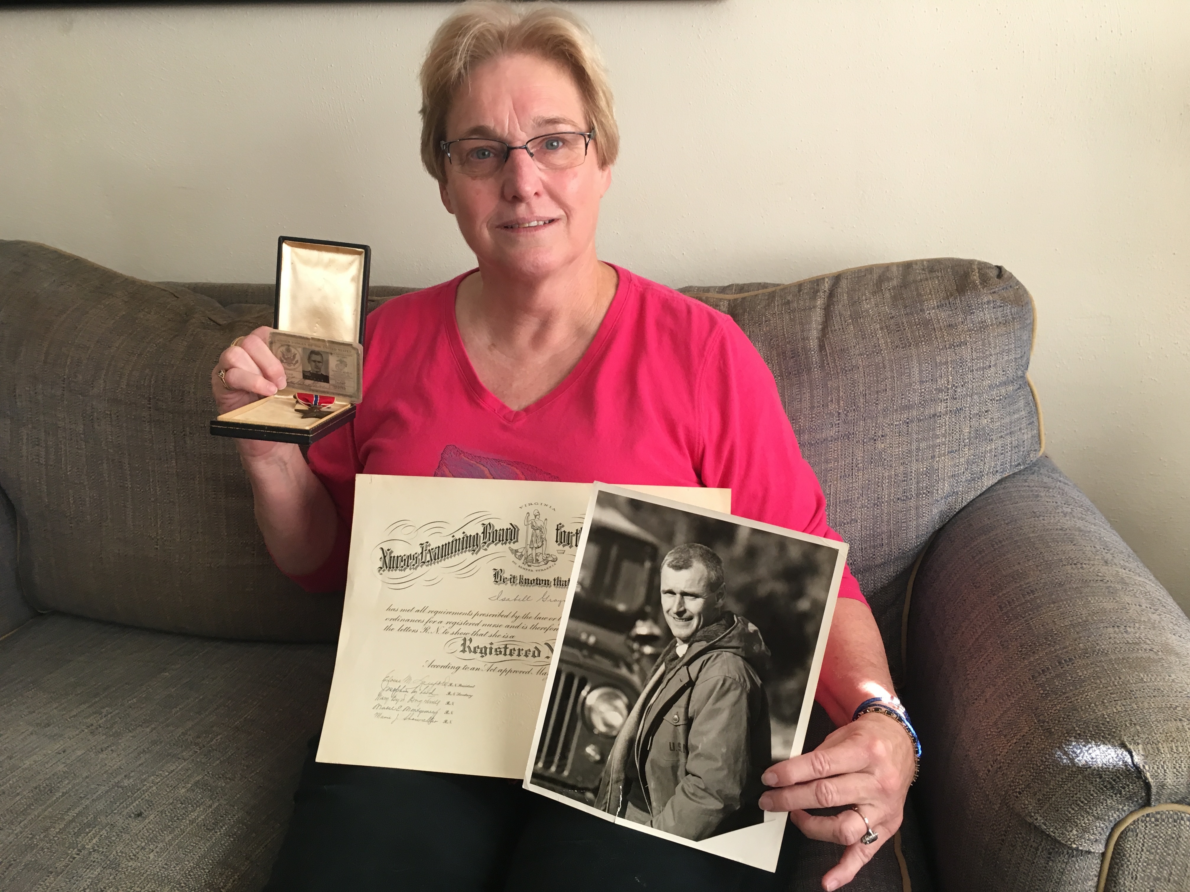 Laurie Staver Clinton holds her parents' World War II memorabilia. (Sarah McCammon/NPR)