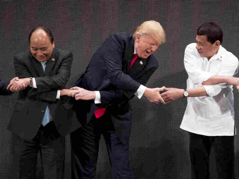President Trump reacts as he does the "ASEAN-way handshake" with Vietnamese Prime Minister Nguyen Xuan Phuc (left) and Philippine President Rodrigo Duterte on stage during the opening ceremony at the ASEAN Summit at the Cultural Center of the Philippines on Monday.