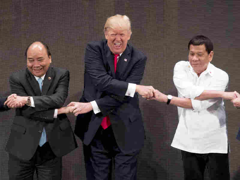President Trump reacts as he does the "ASEAN-way handshake" with Vietnamese Prime Minister Nguyen Xuan Phuc (left) and Philippine President Rodrigo Duterte on stage during the opening ceremony at the ASEAN Summit at the Cultural Center of the Philippines on Monday.